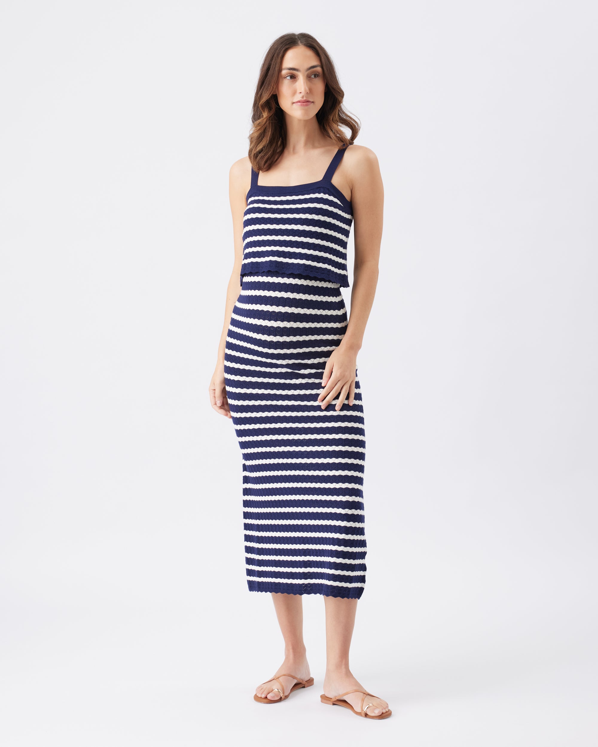 Woman wearing a navy and white striped knitted dress on a white background