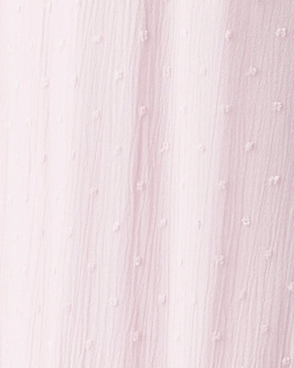 A close-up of a pale pink textured fabric with a subtle dotted or raised-dot pattern and soft vertical folds.