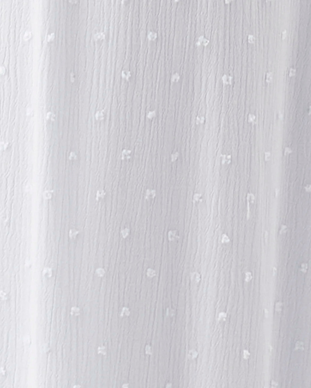 A close-up of a white textured fabric with a subtle dotted pattern and vertical folds.