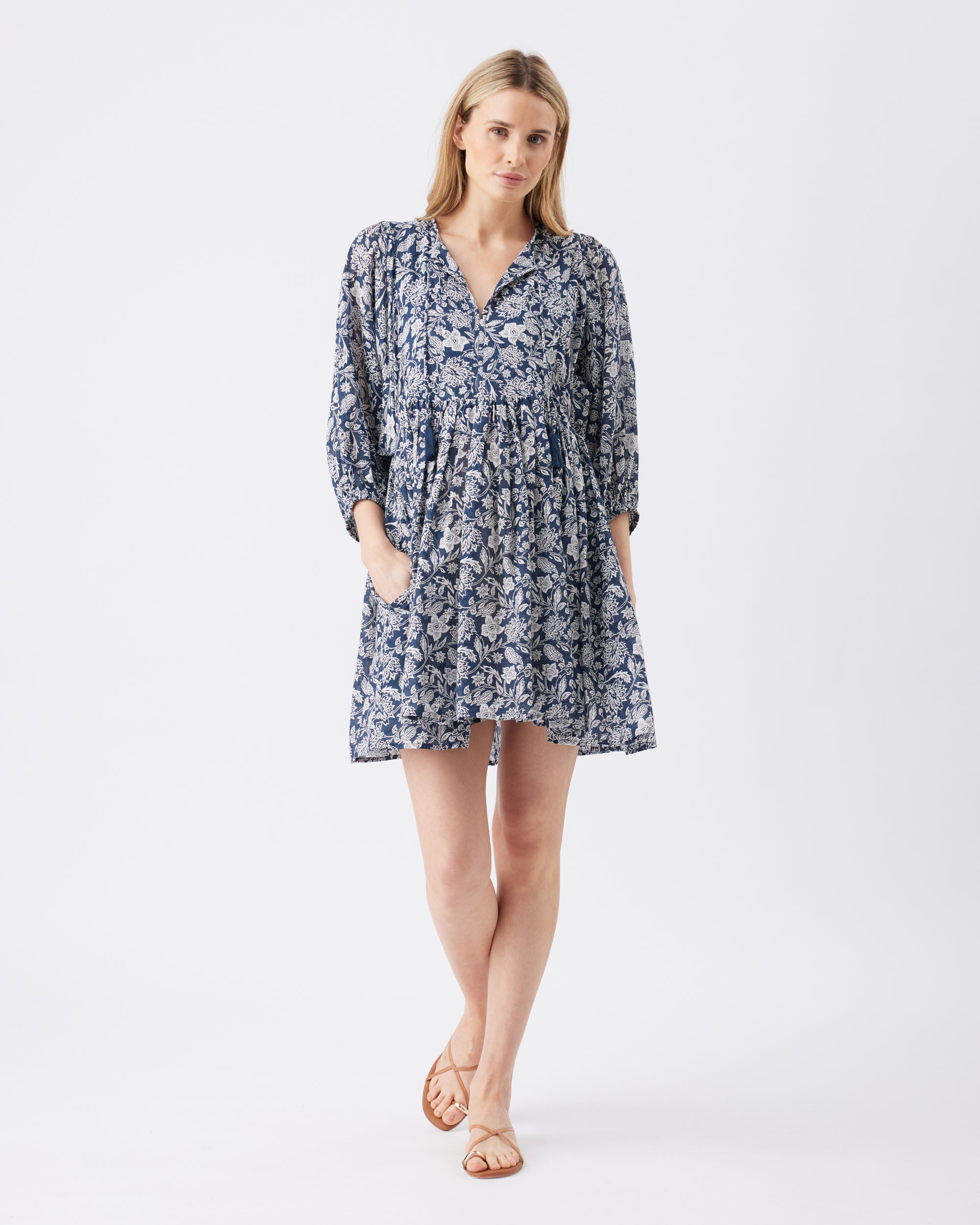 Full lenght shot of a woman wearing a blue floral dress on a white background