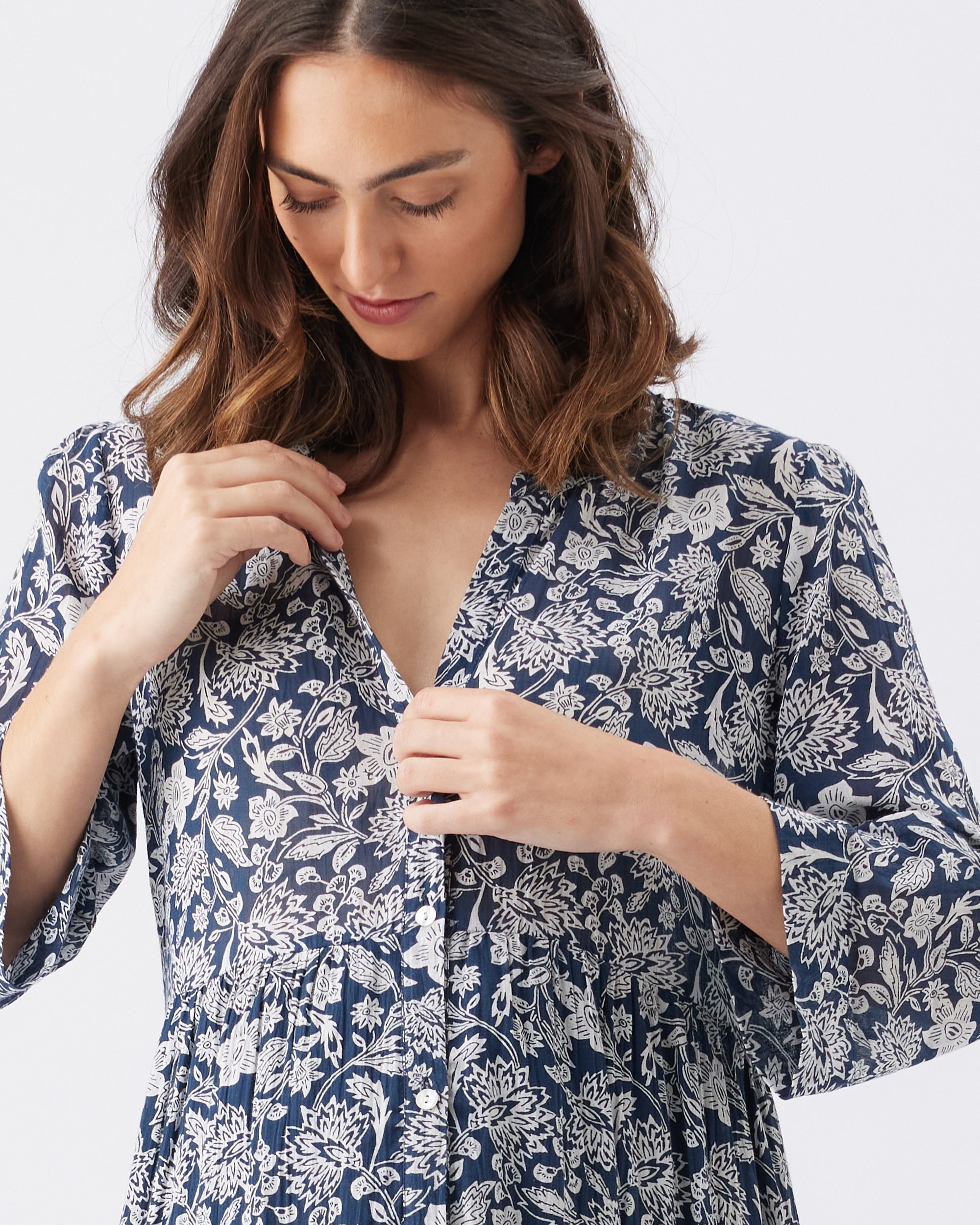 Woman wearing a blue floral dress against a white background