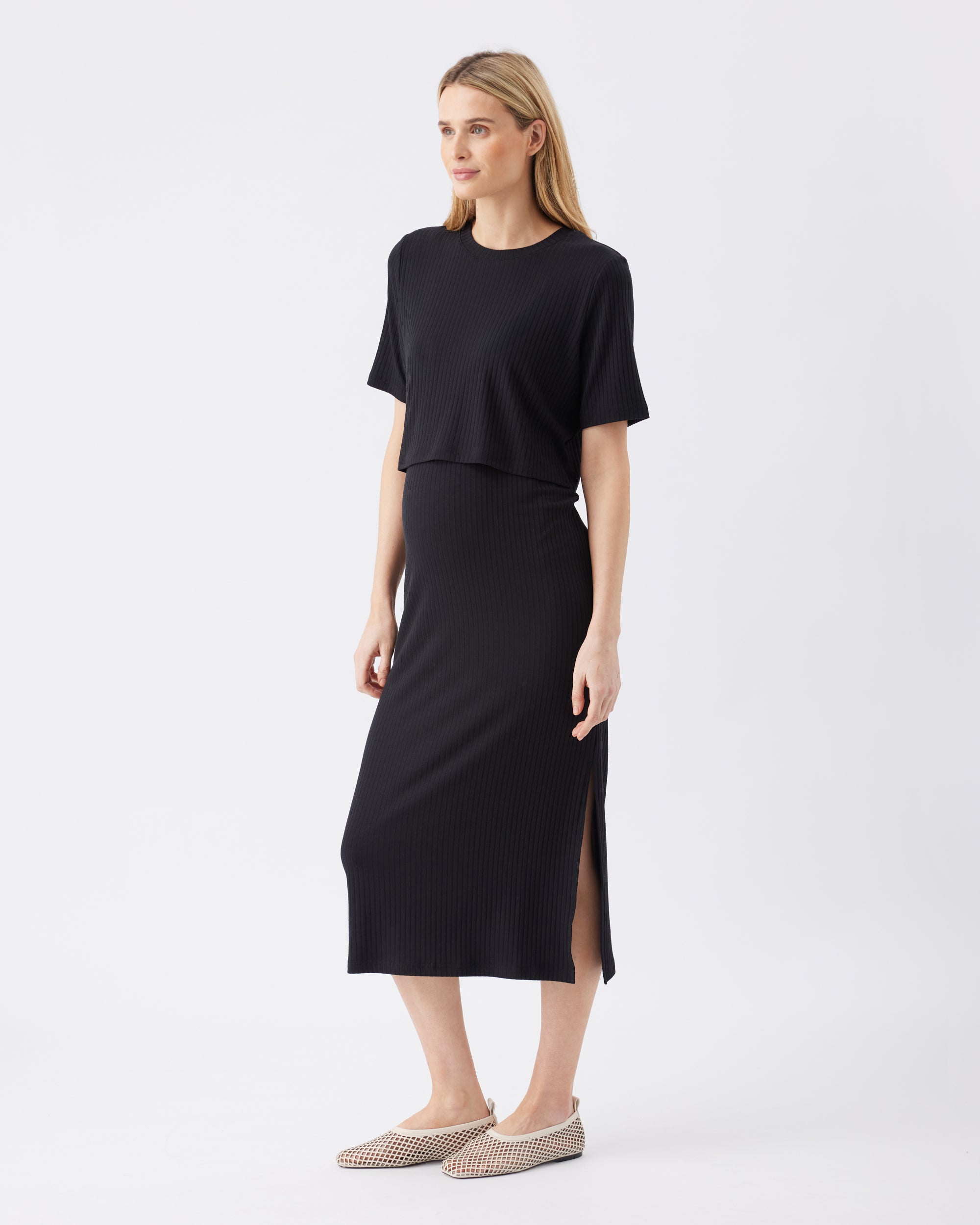 Woman wearing a black outfit with a split skirt on a white background