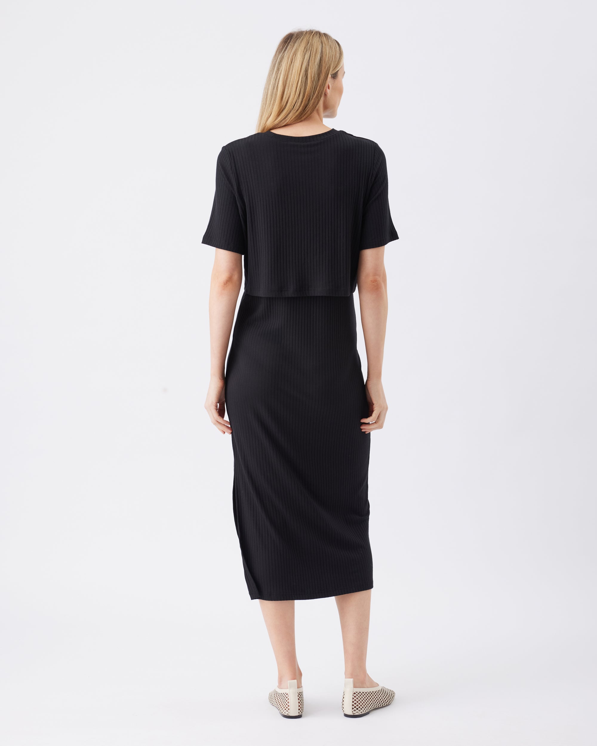 Back view of a woman wearing a black dress on a white background