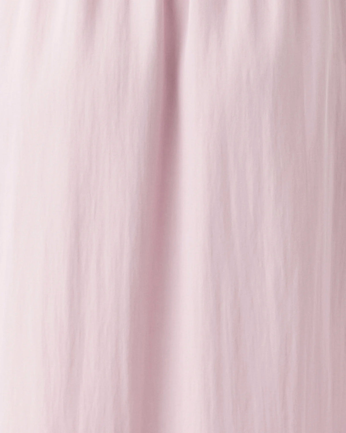 A close-up of a light pink fabric with soft vertical folds and a smooth texture.