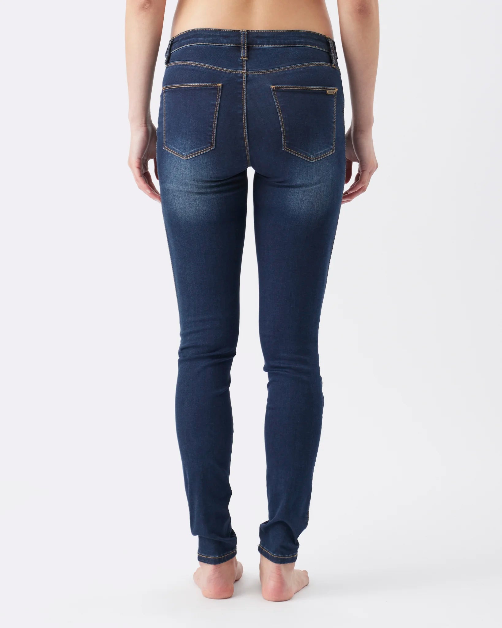 Rear view of a model wearing dark blue skinny jeans with a faded wash, showing the back pockets and waistband details against a plain white background.