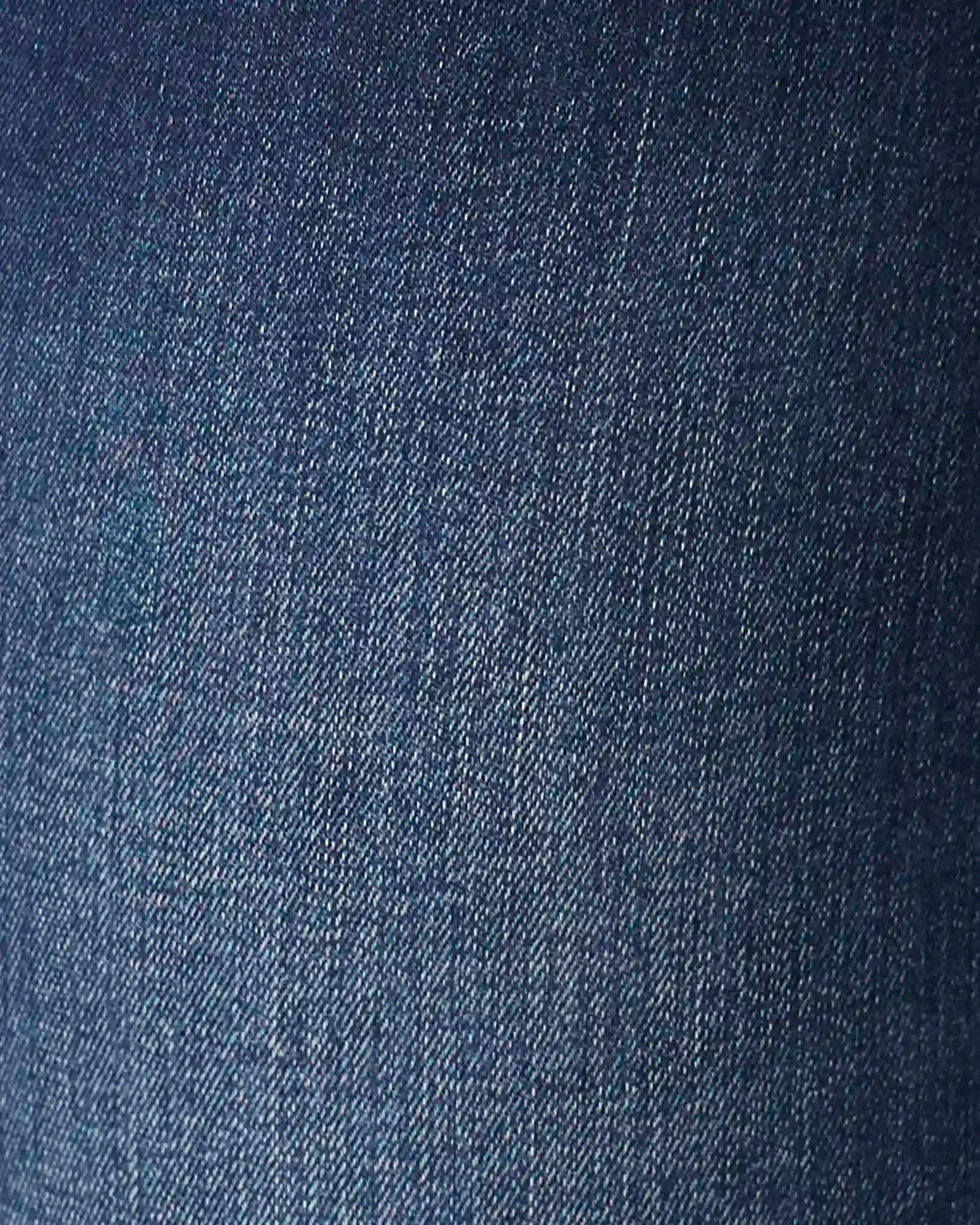 A close-up texture shot of dark blue denim fabric, showing the twill weave pattern.