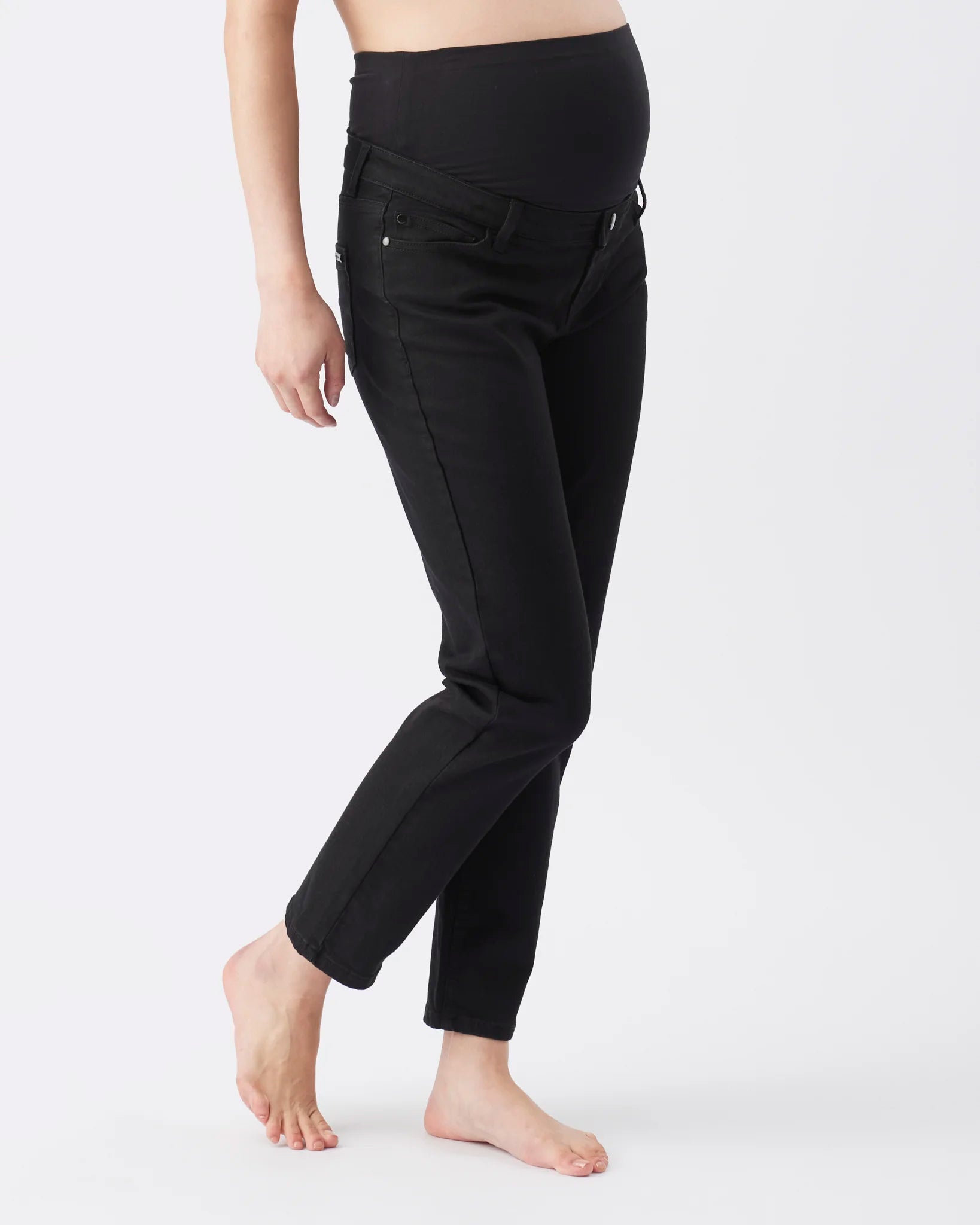 Black maternity pants with an elastic belly band, shown on a model from the waist down against a white studio background.