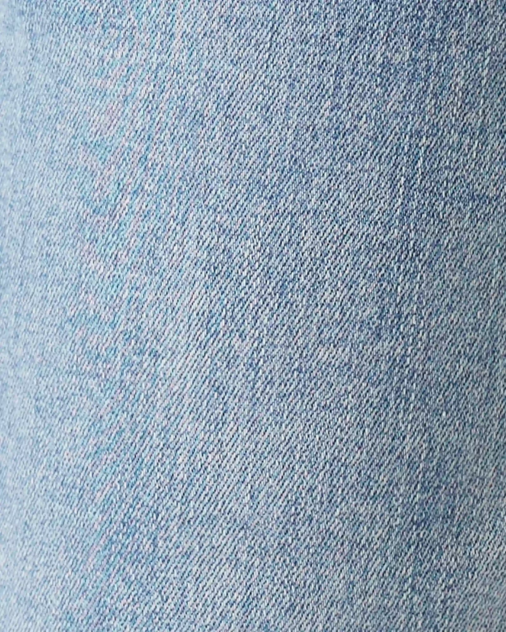 A close-up texture shot of light blue denim fabric, showing the detailed twill weave pattern.