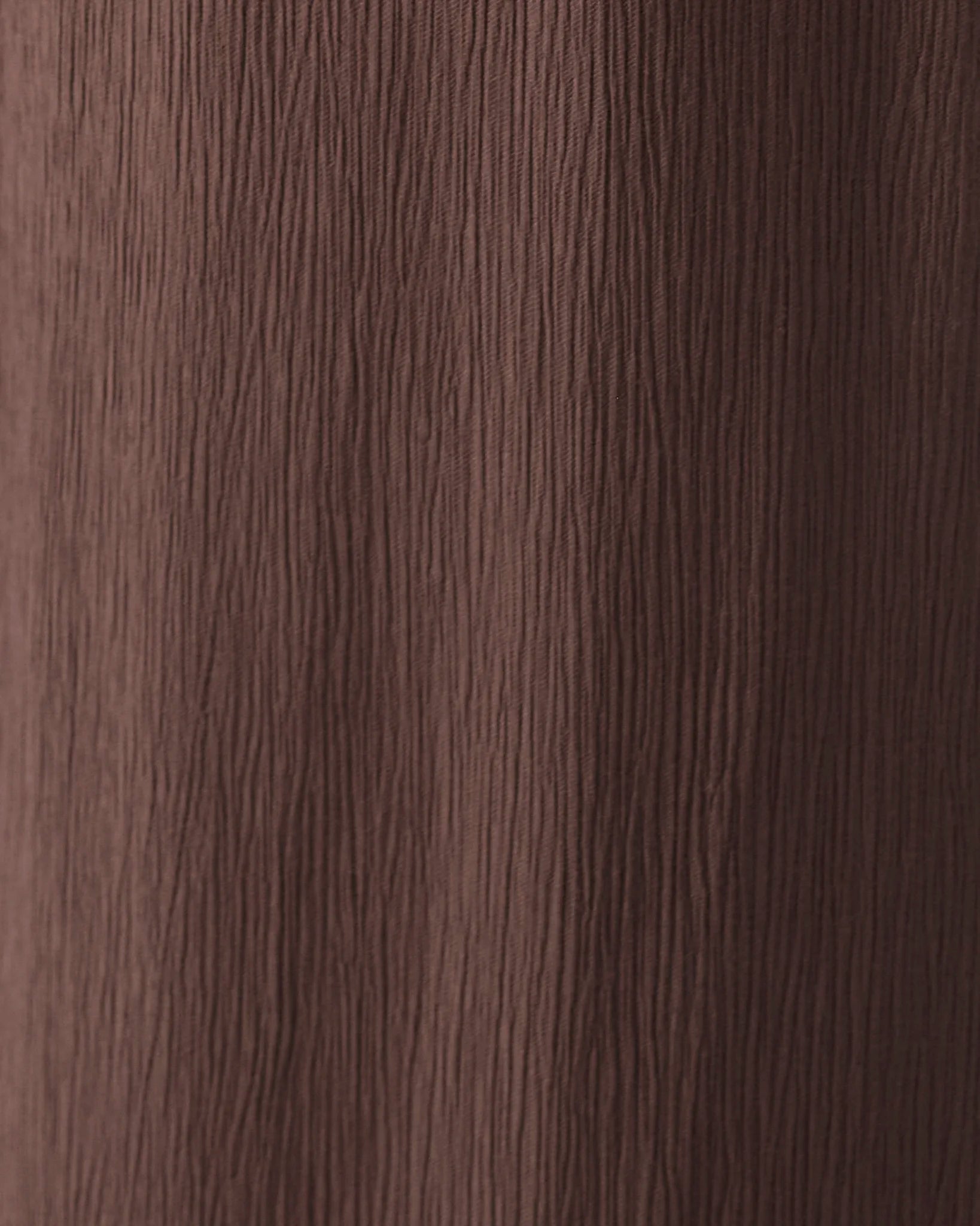 A close-up texture of dark brown wood grain with vertical lines.