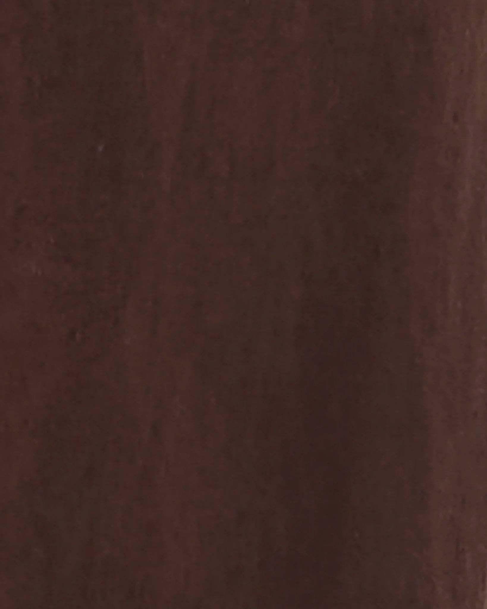 A close-up texture swatch of dark brown leather or suede material.