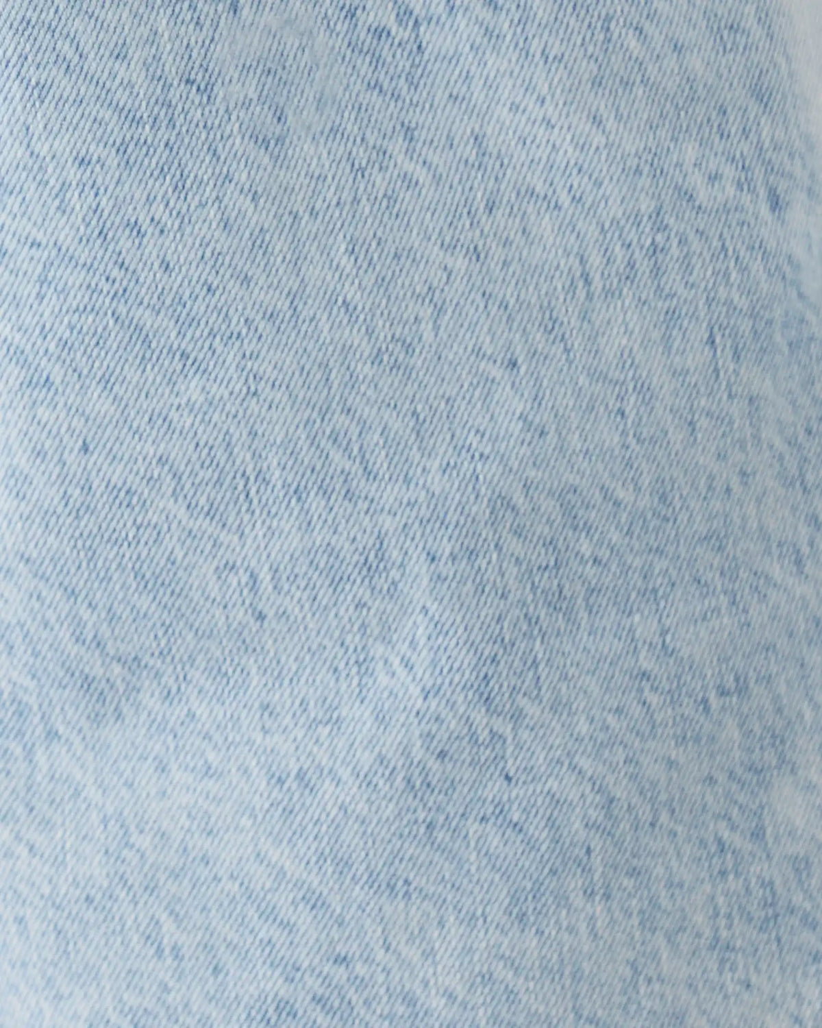 A close-up of light blue denim fabric texture with subtle fading and woven twill pattern.