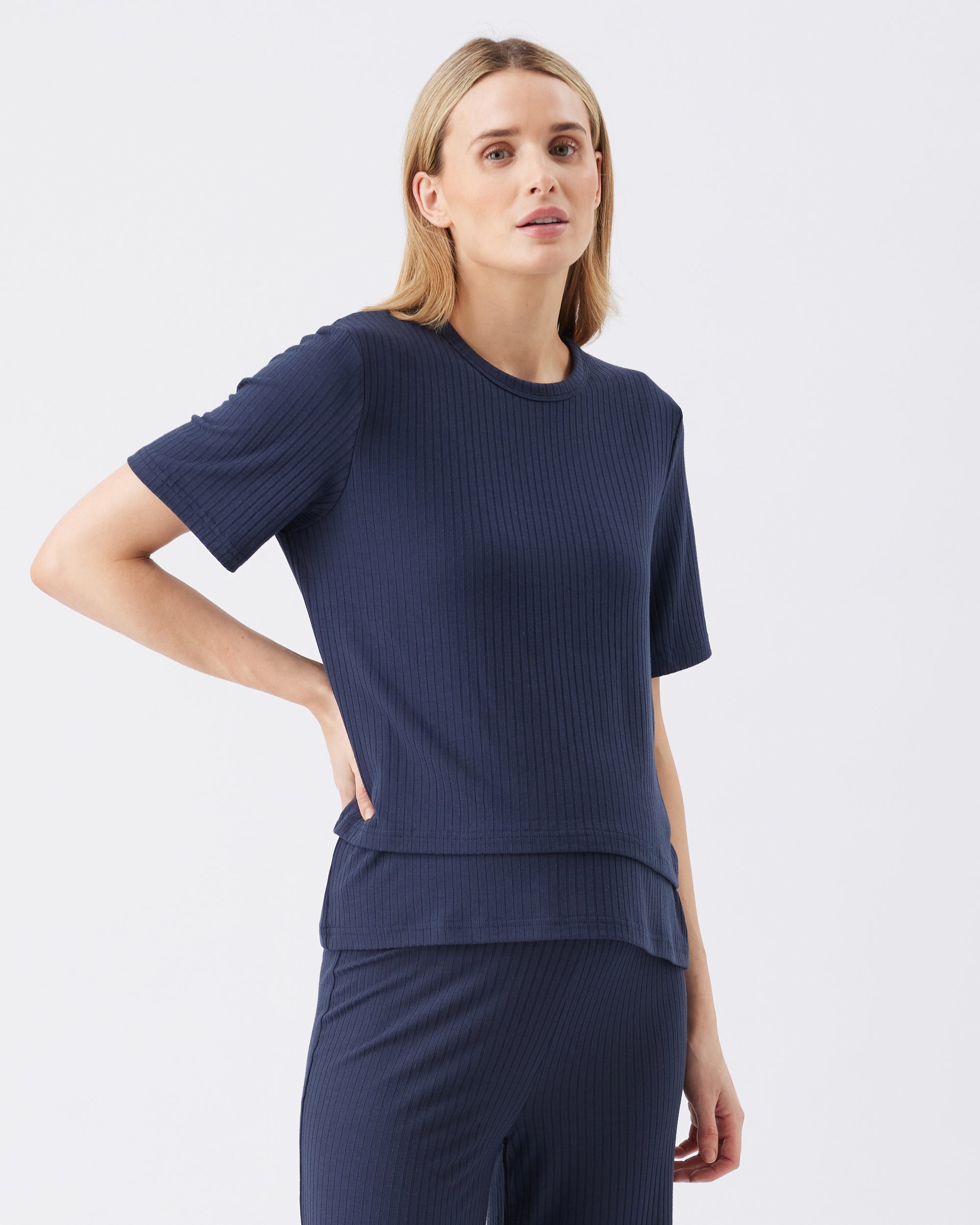 Woman wearing a navy blue ribbed top and pants on a white background
