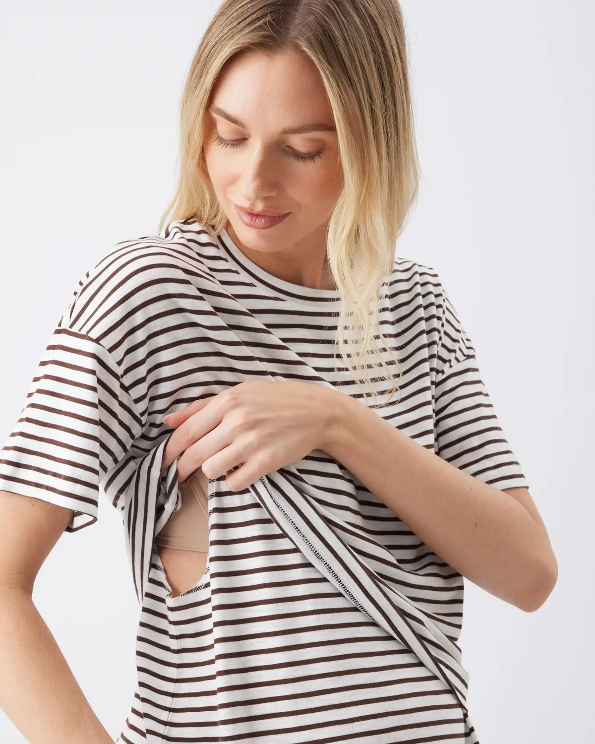 A woman wearing a black and white horizontally striped short-sleeve t-shirt with a front lift up access shown from the chest up against a light gray background.
