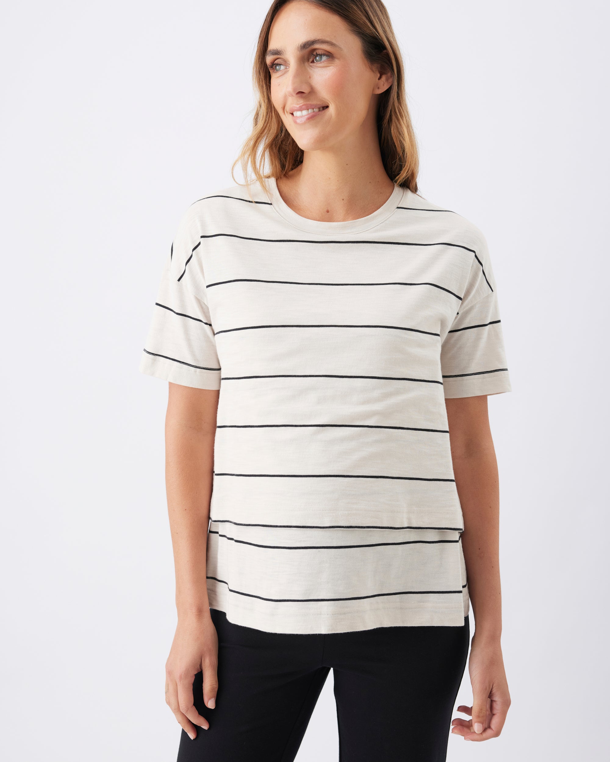 Pregnant woman wearing a white t-shirt with black horizontal stripes on a plain background