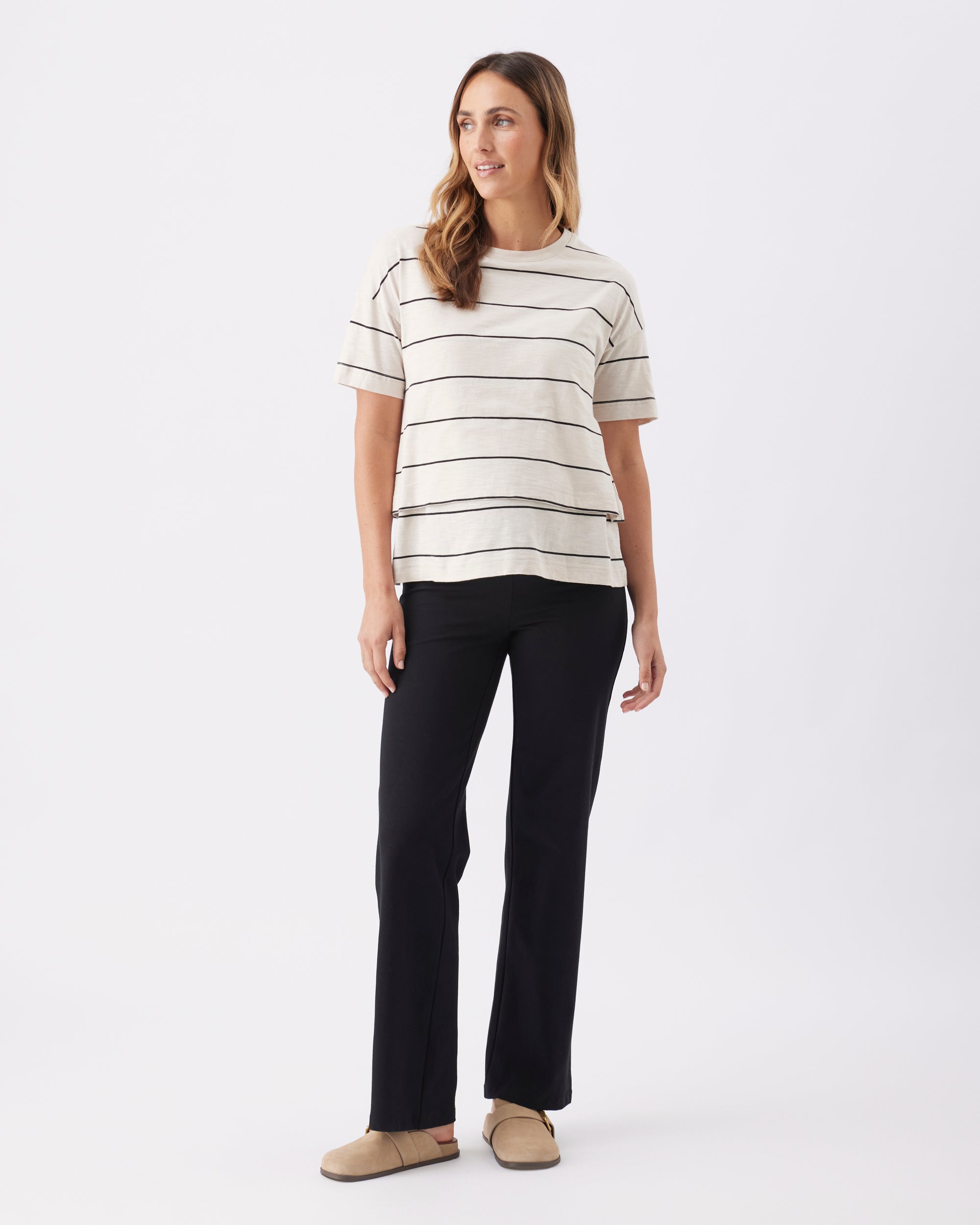 Full lenght view of a pregnant woman wearing a striped shirt and black pants on a white background