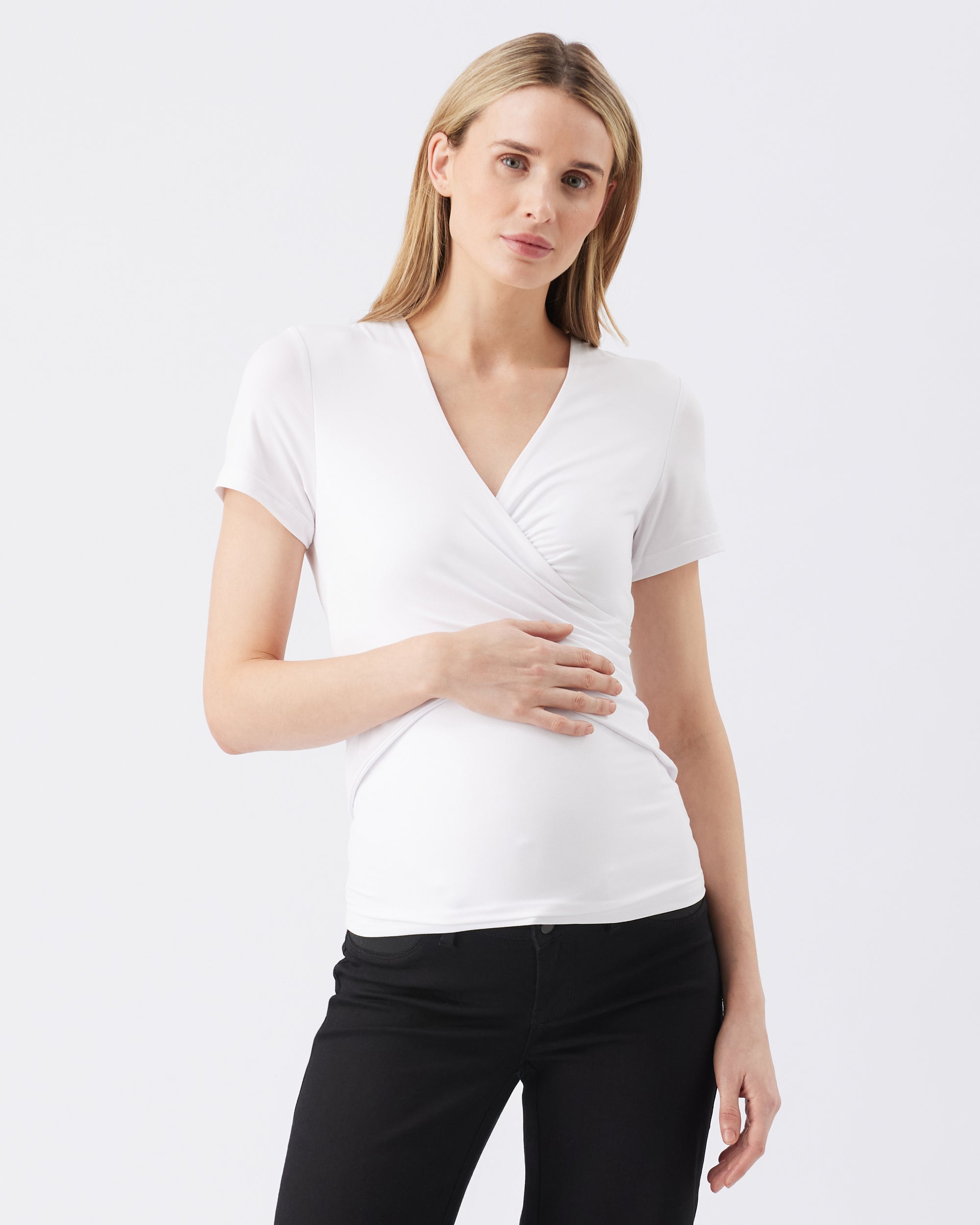 Woman wearing a white short-sleeve top and black pants on a light gray background