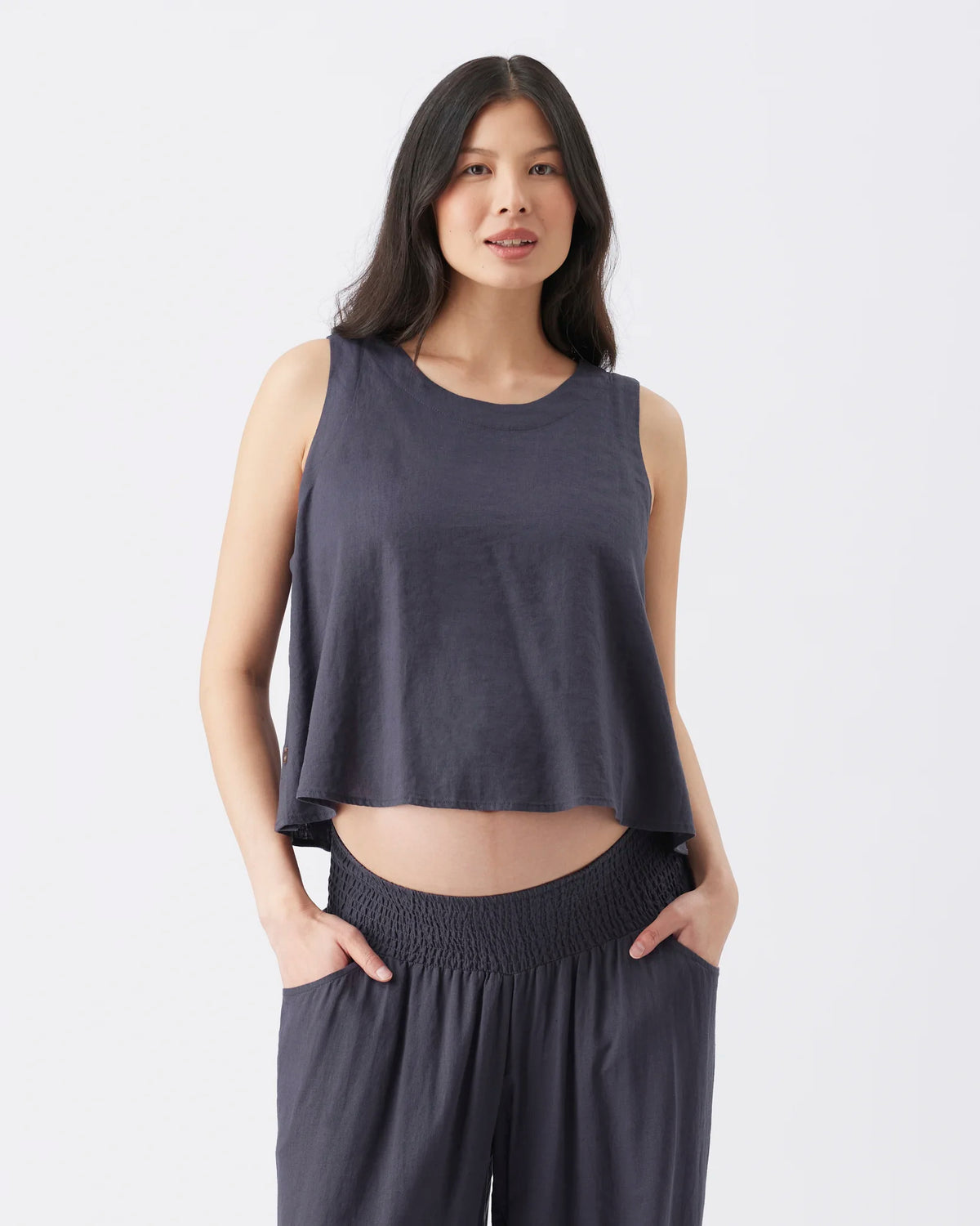 A woman modeling a dark slate gray sleeveless crop top and matching wide-leg pants against a clean white studio background.