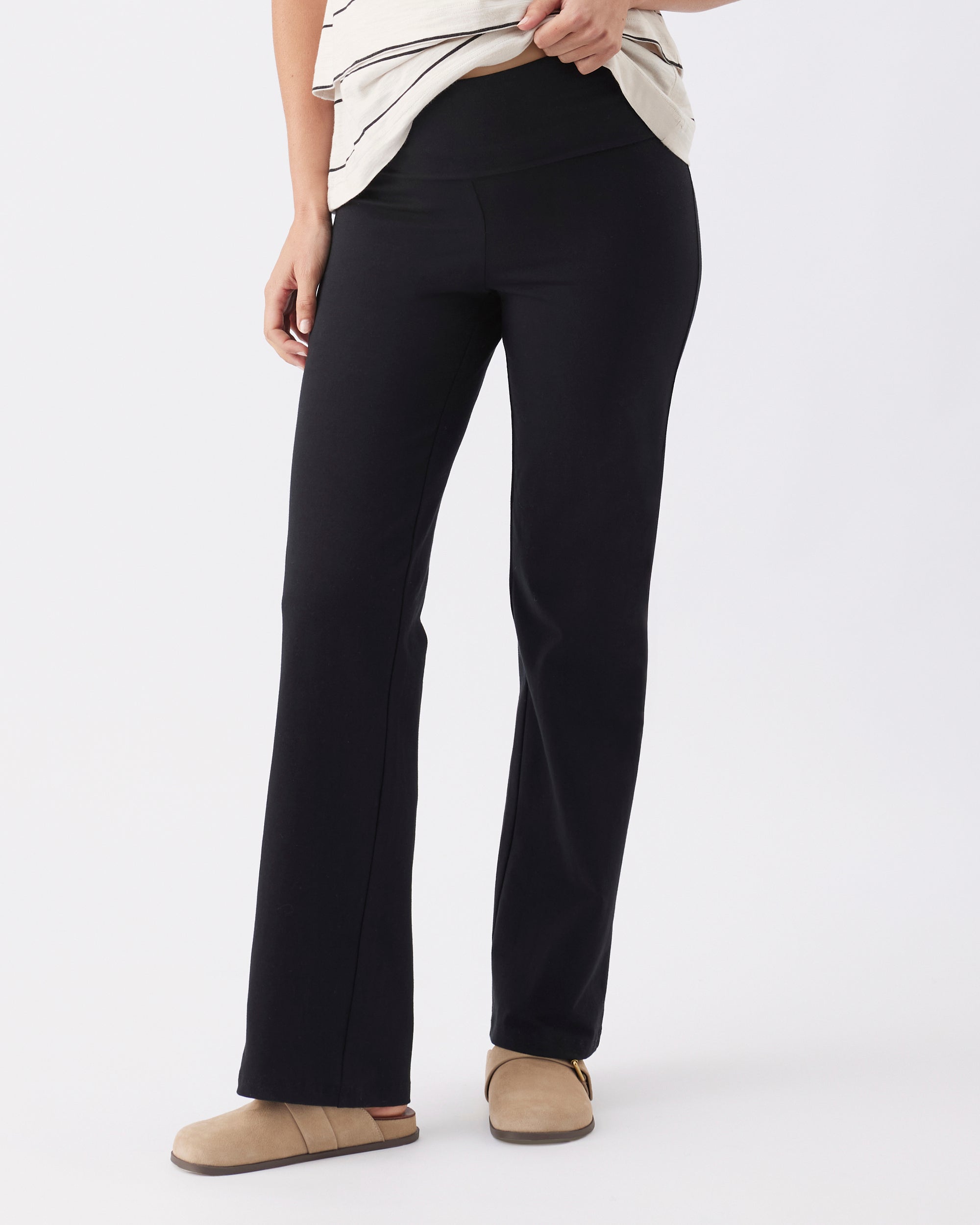 Person wearing straight leg black pants on a white background