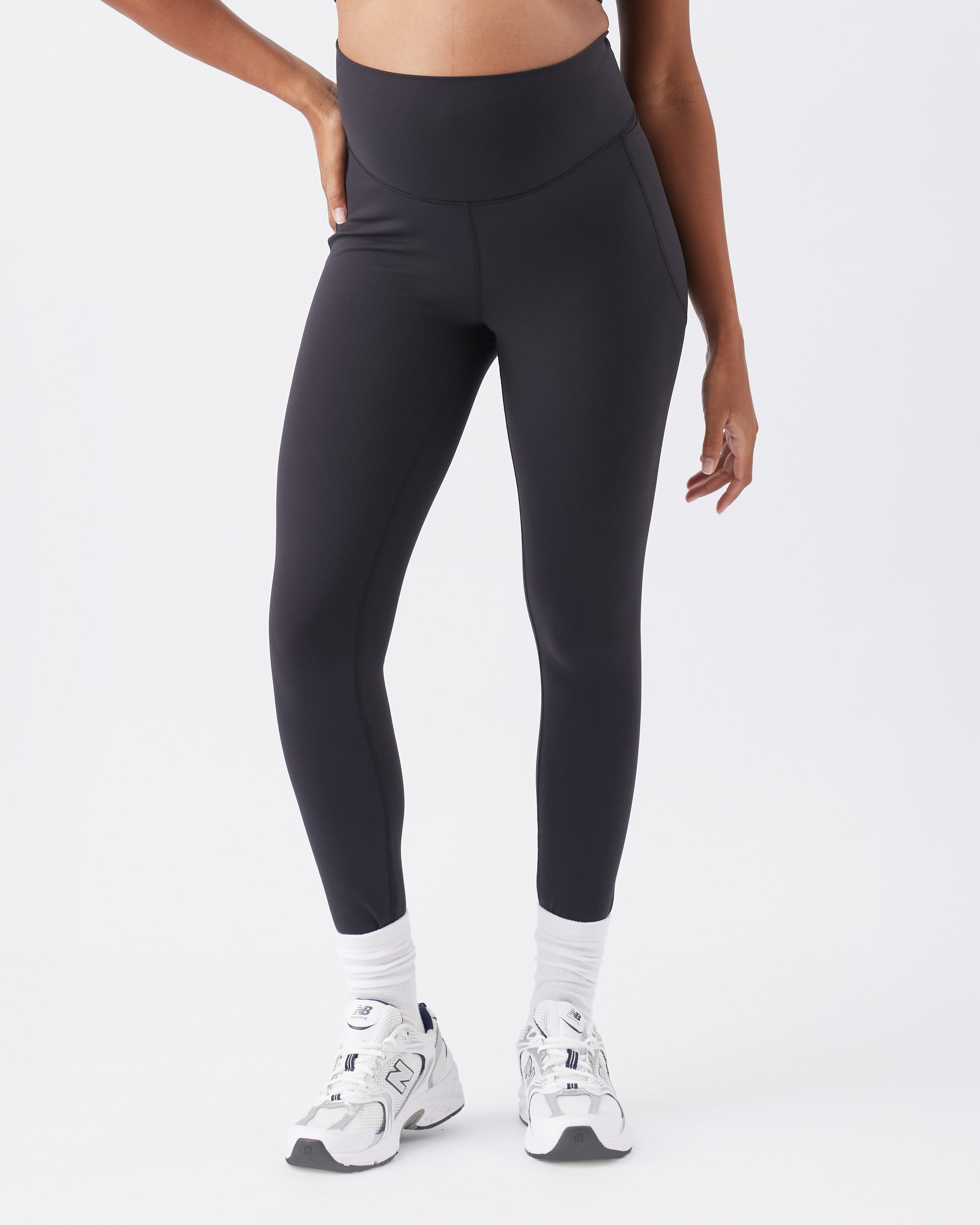 Woman wearing black leggings and white sneakers on a white background