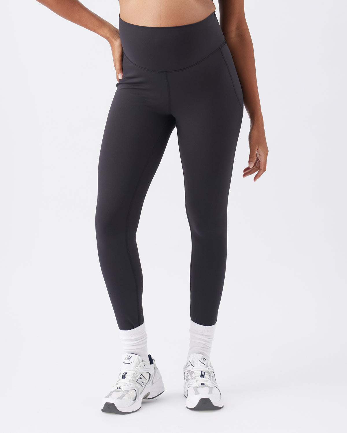 Woman wearing black leggings and white sneakers on a white background