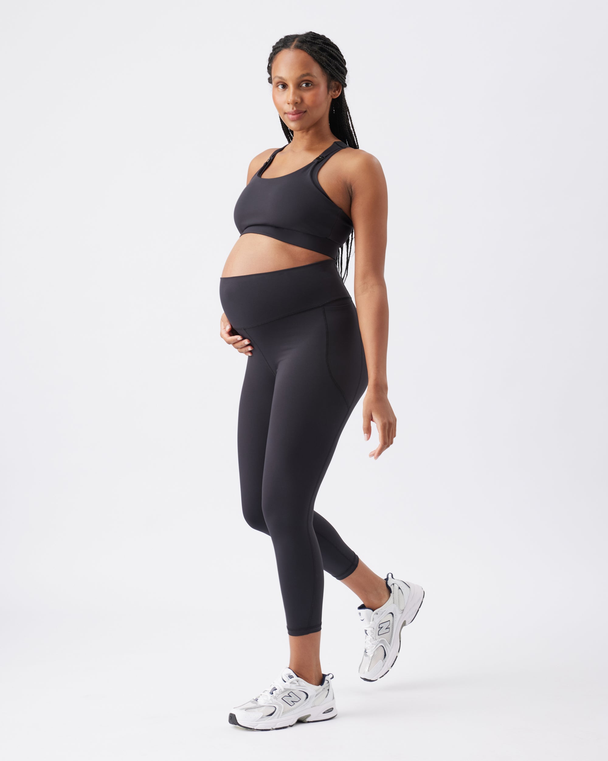 Pregnant woman wearing a black athletic outfit on a white background