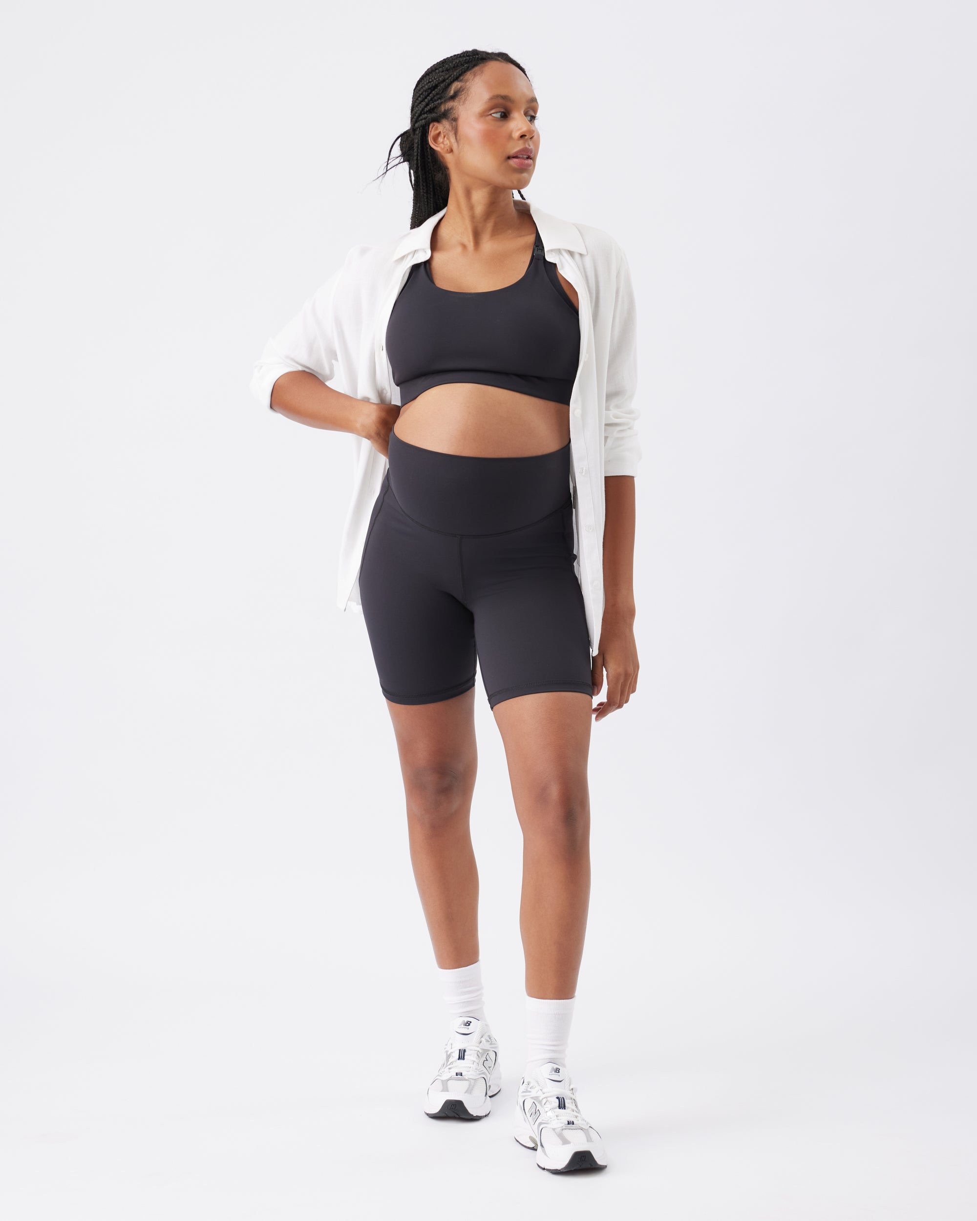 Woman wearing a black athletic outfit with a white jacket on a white background