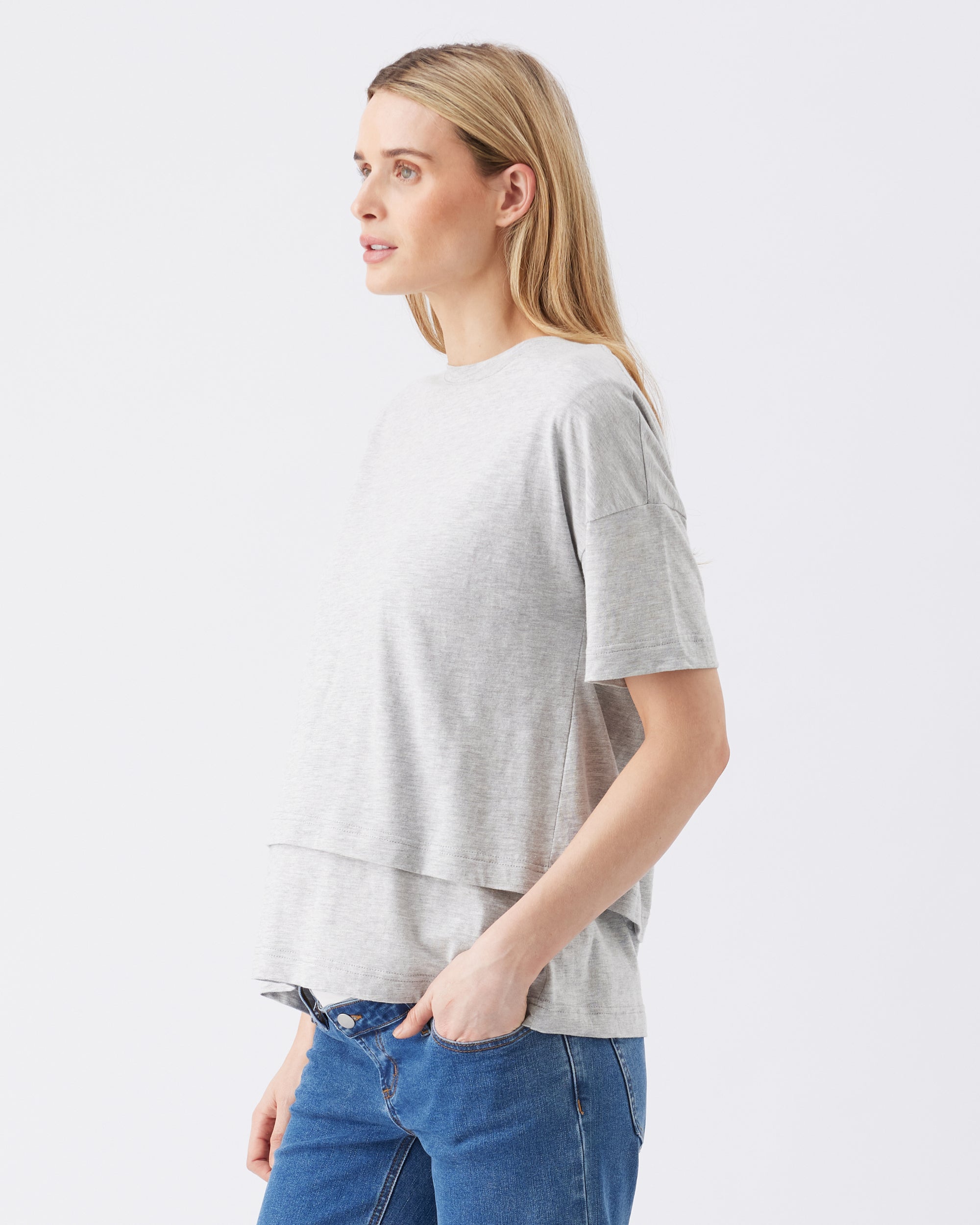 Woman wearing a gray t-shirt and blue jeans on a white background