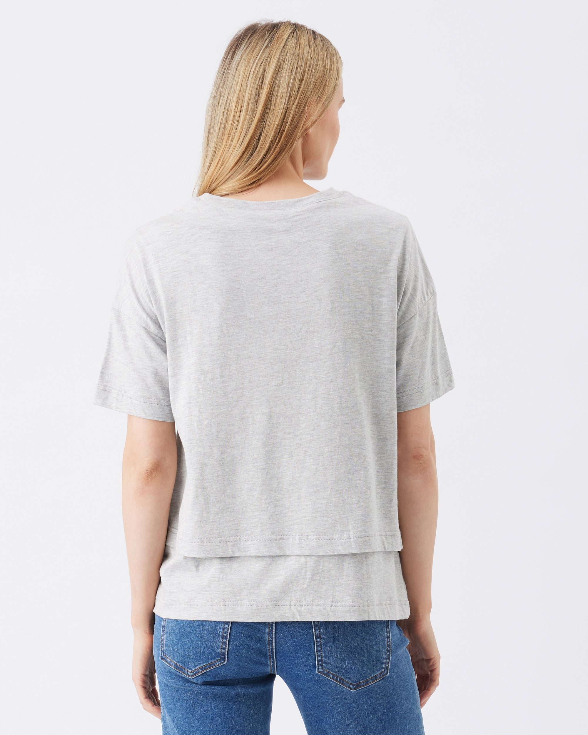 Person wearing a gray t-shirt and blue jeans on a white background
