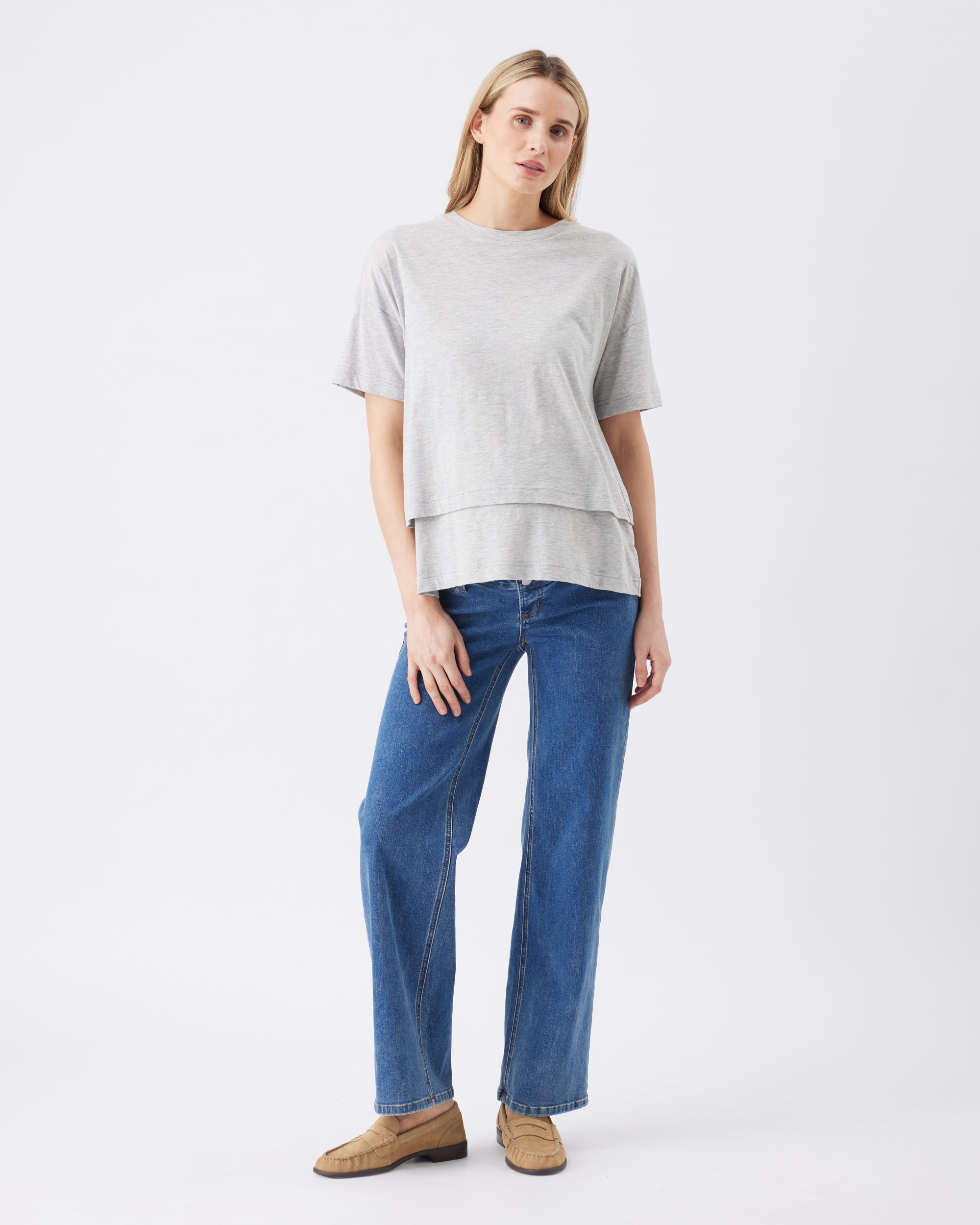 Woman wearing a gray top and blue jeans on a white background