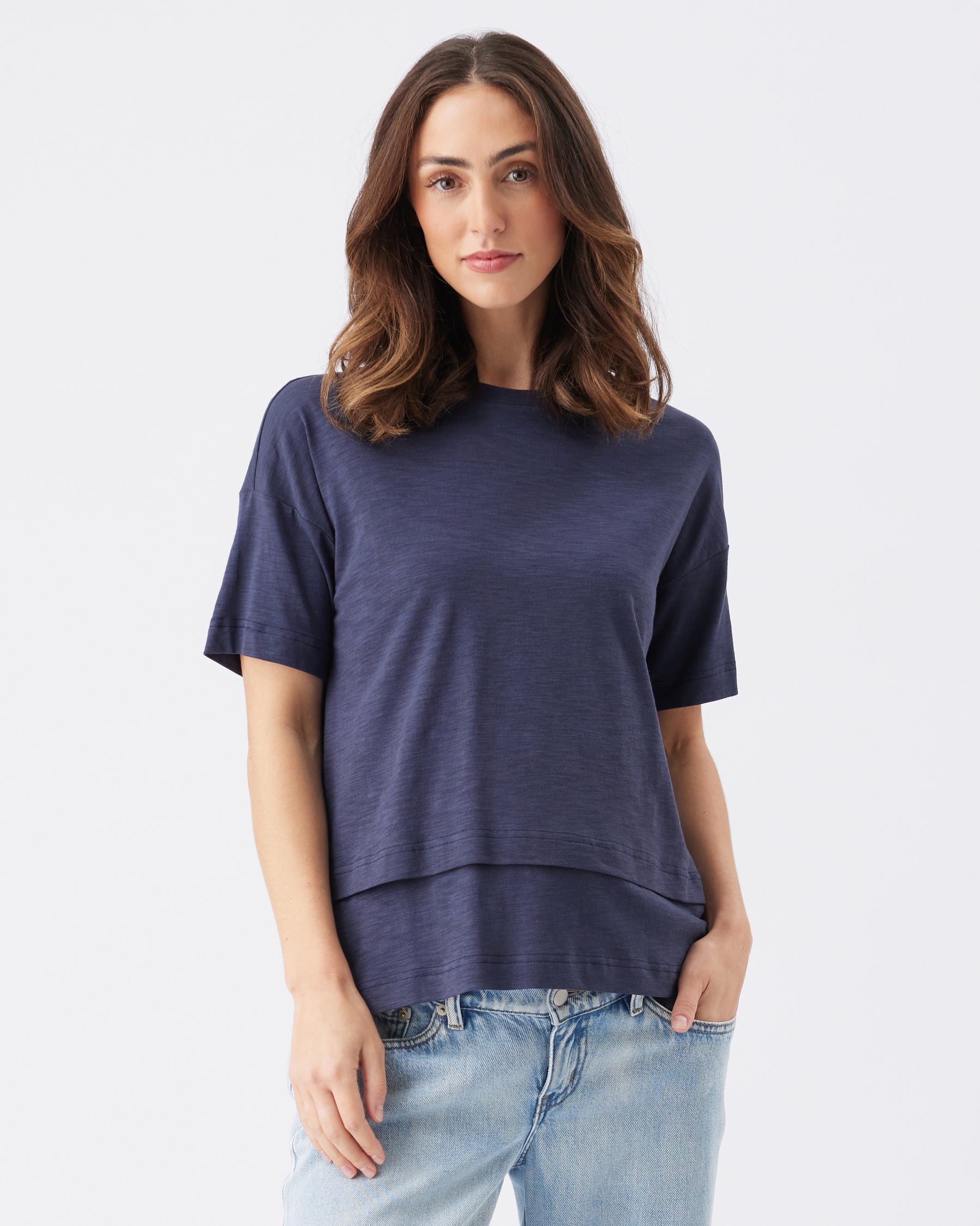 Woman wearing a navy blue t-shirt and light blue jeans on a white background