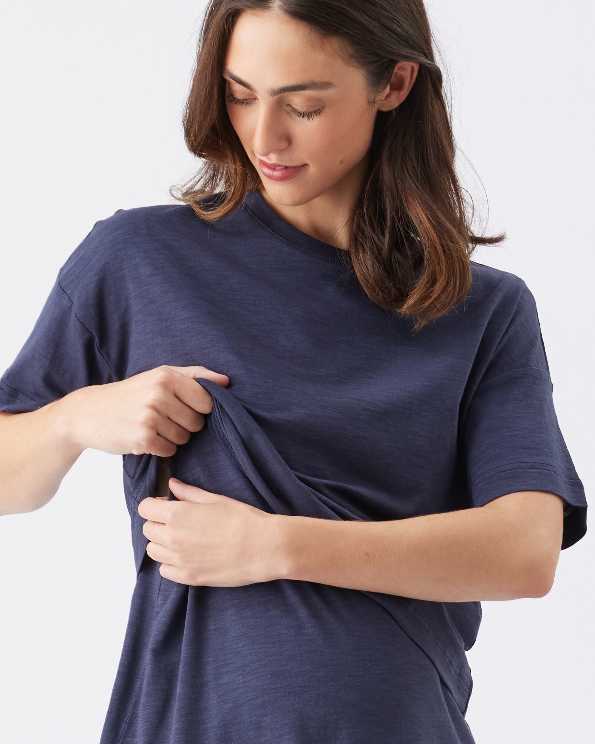 Woman lifing up the front nursing panel of a navy blue t-shirt against a white background
