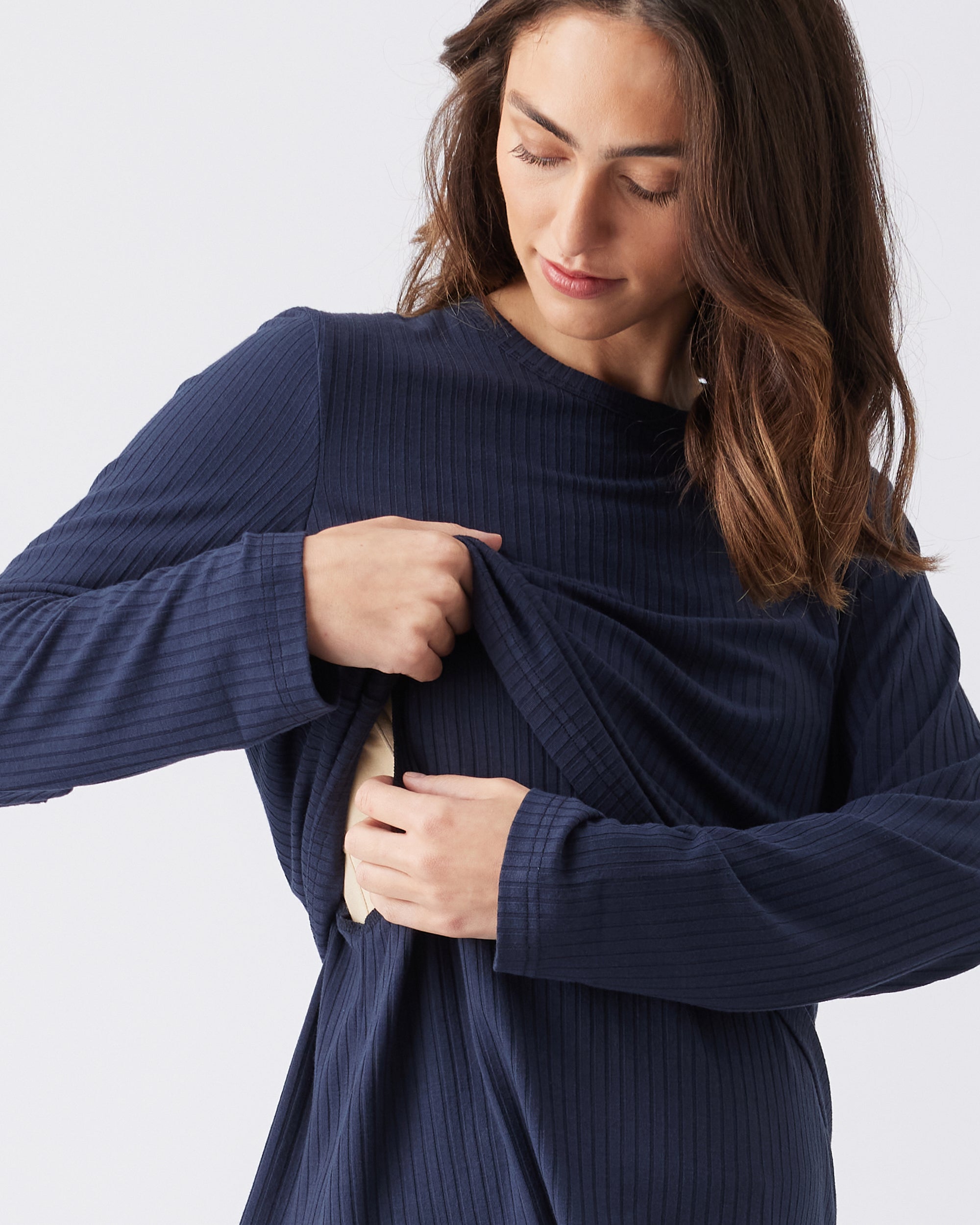 Woman wearing a navy ribbed sweater showing the nursing access against a white background