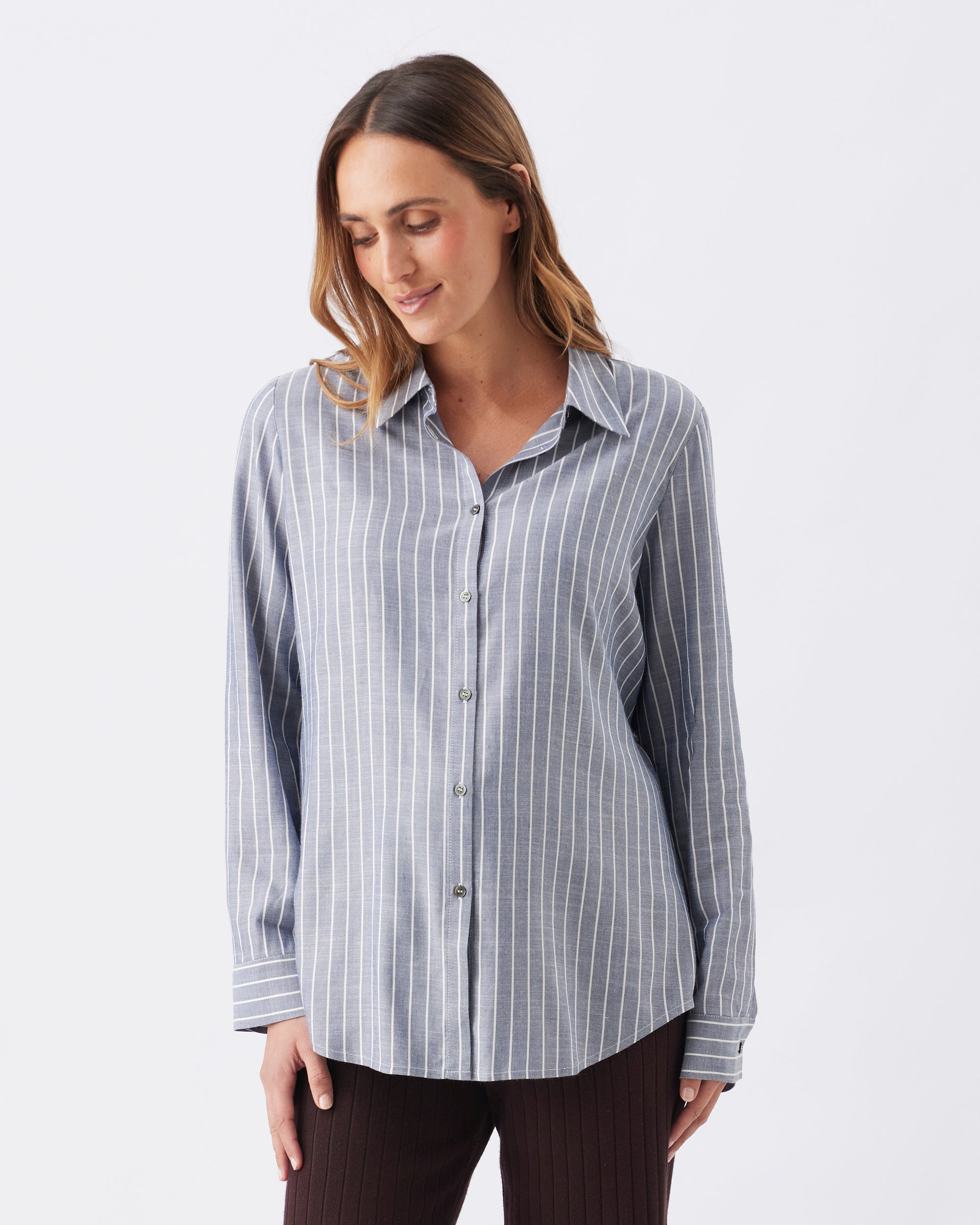 Woman wearing a blue and white long sleeved striped shirt on a light gray background