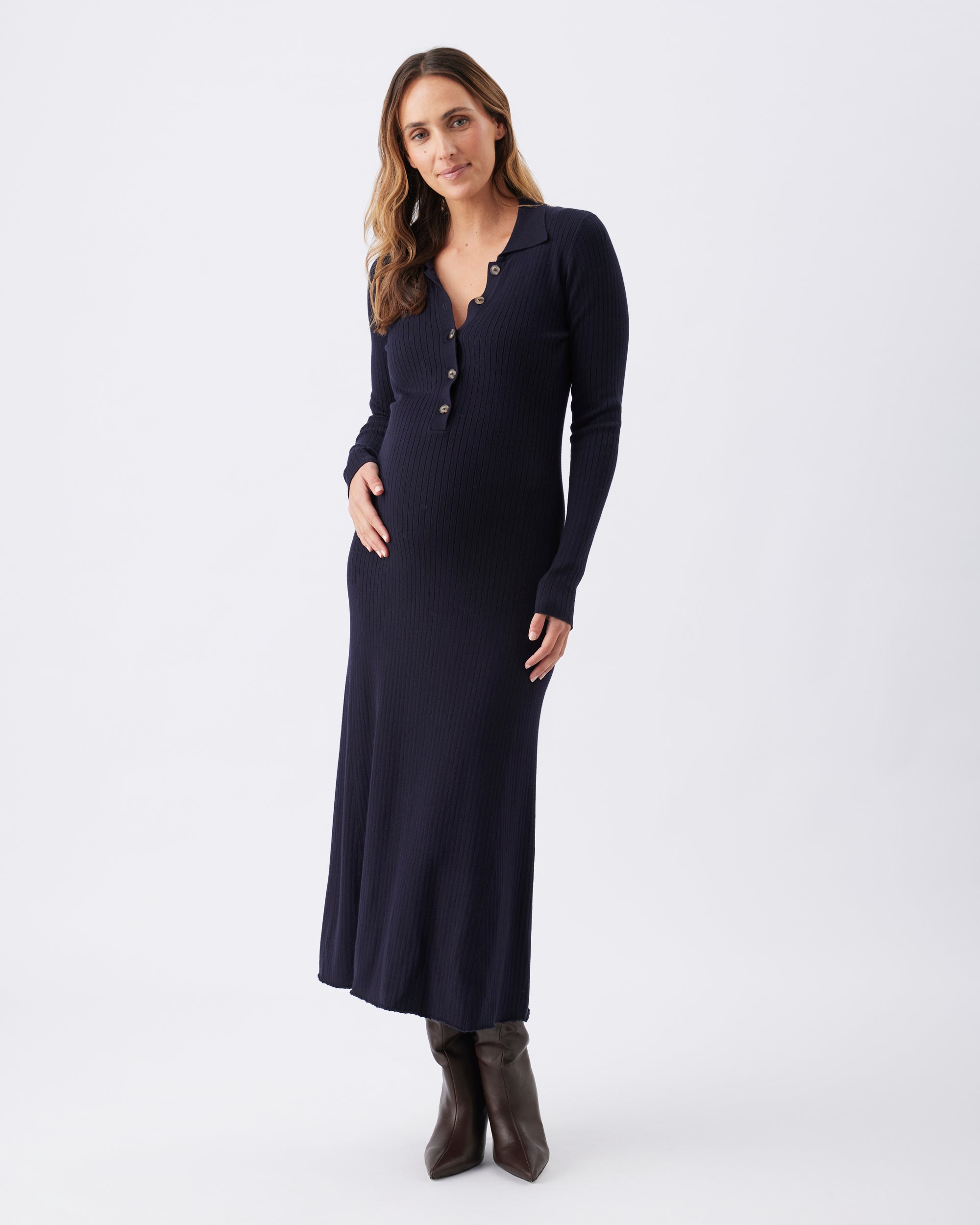 Full length view of a pregnant woman wearing a Hollie Knit Dress in navy blue.