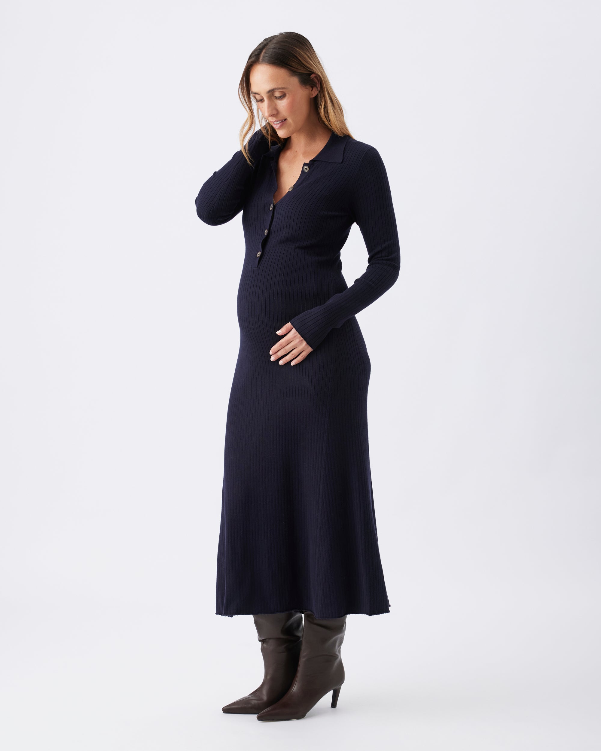 Full length view of a pregnant woman wearing a long sleeved navy blue midi dress.