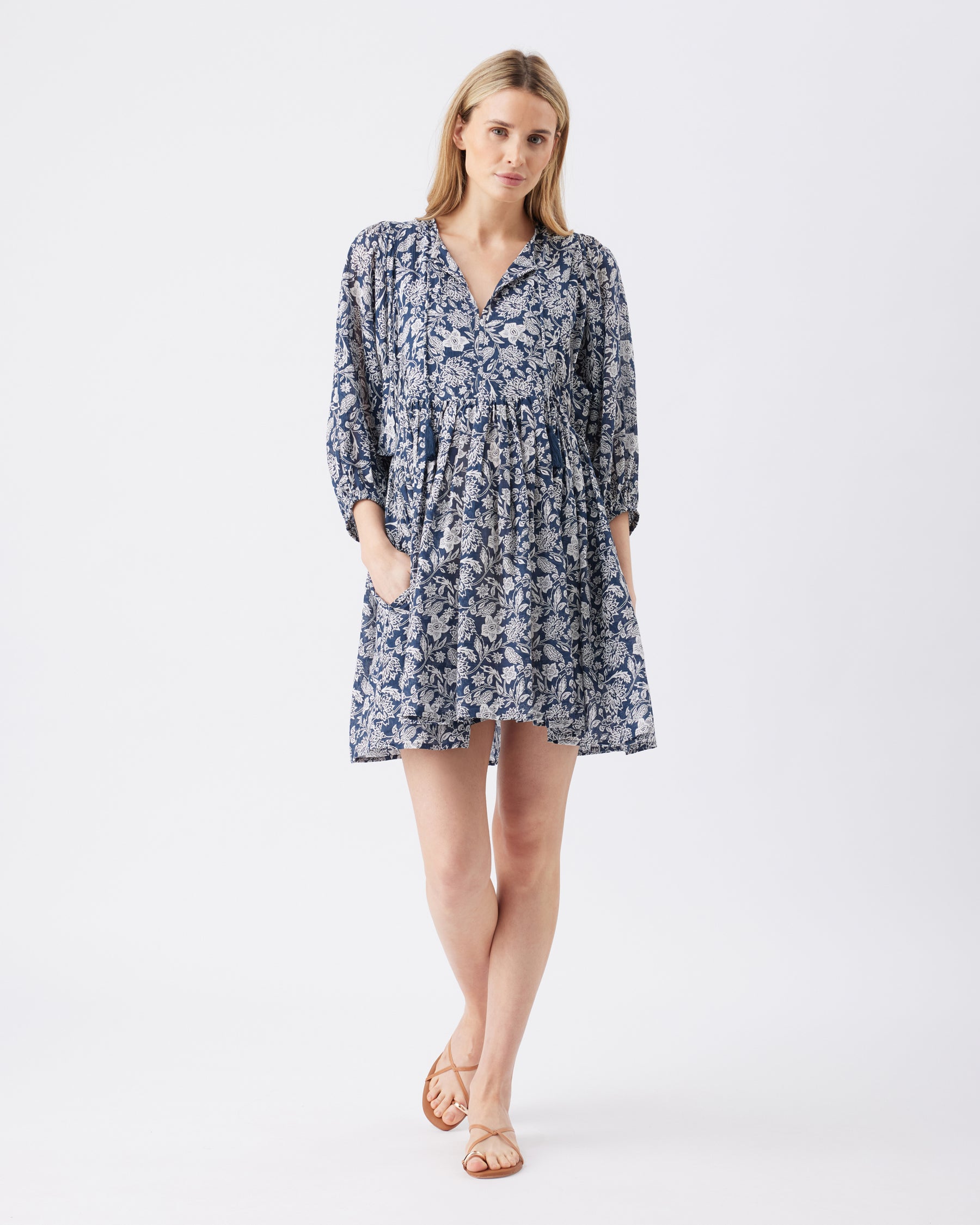 Full lenght shot of a woman wearing a blue floral dress on a white background