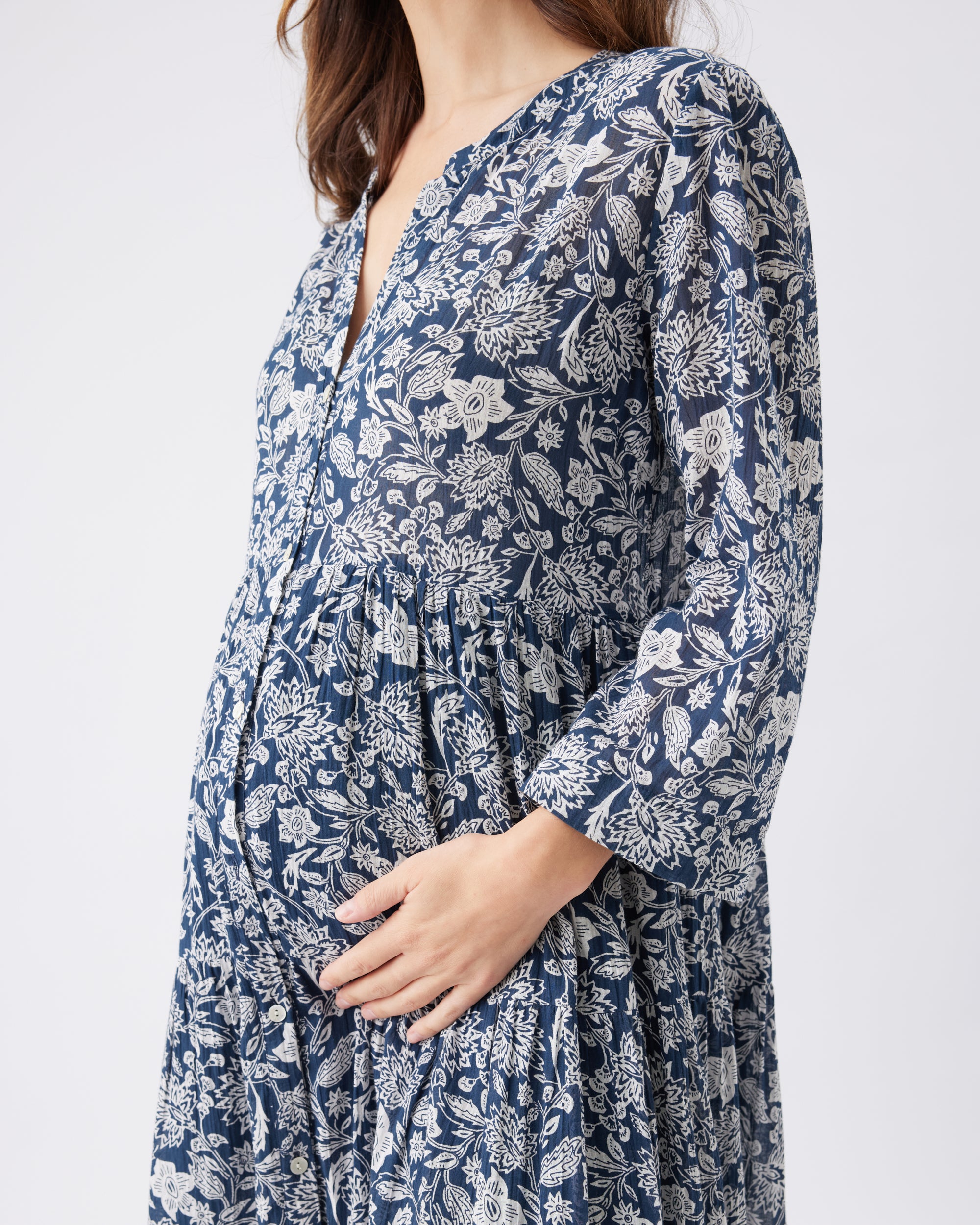 Closeup of a woman wearing a blue floral dress on a white background