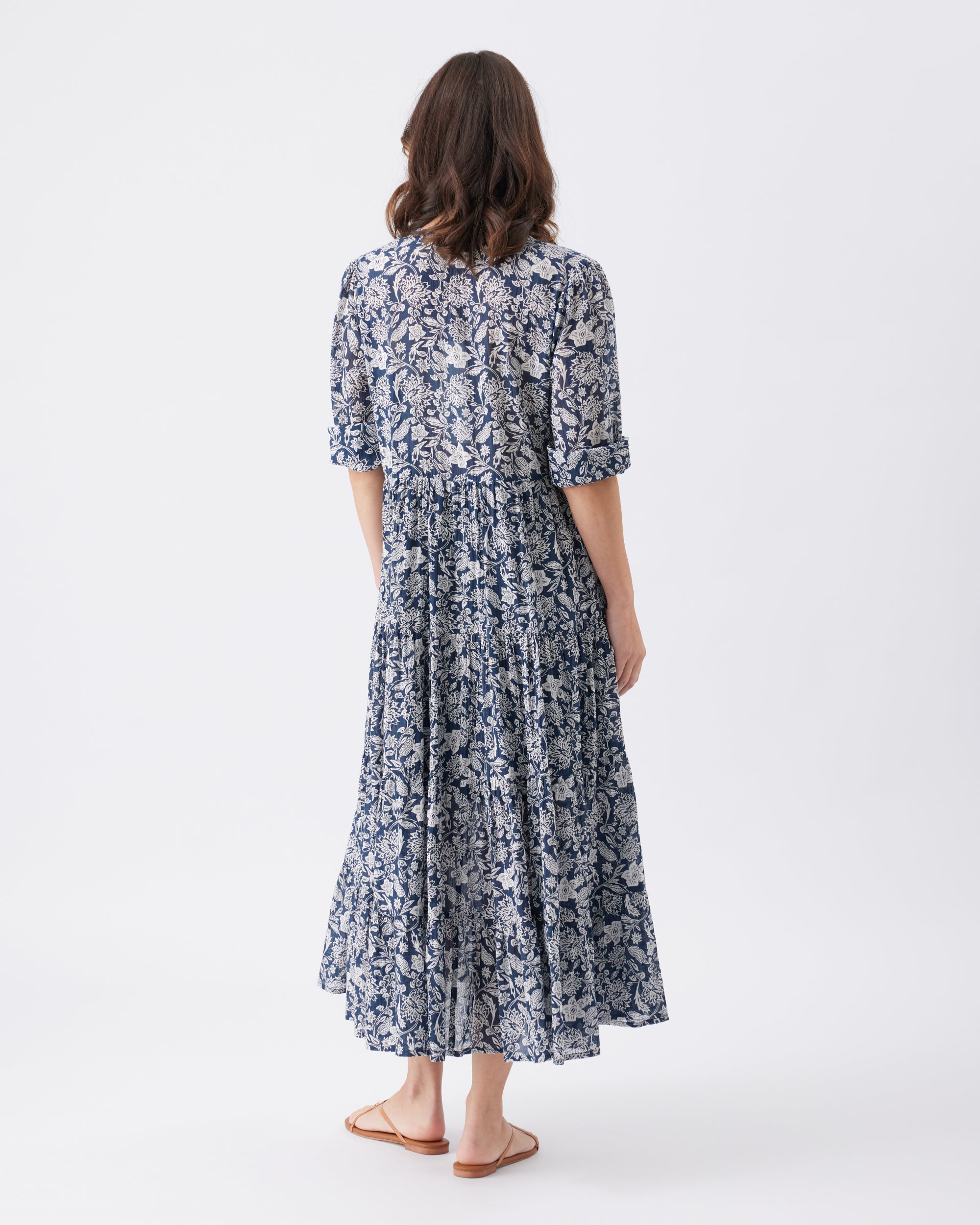 Back view of a woman wearing a floral dress on a white background
