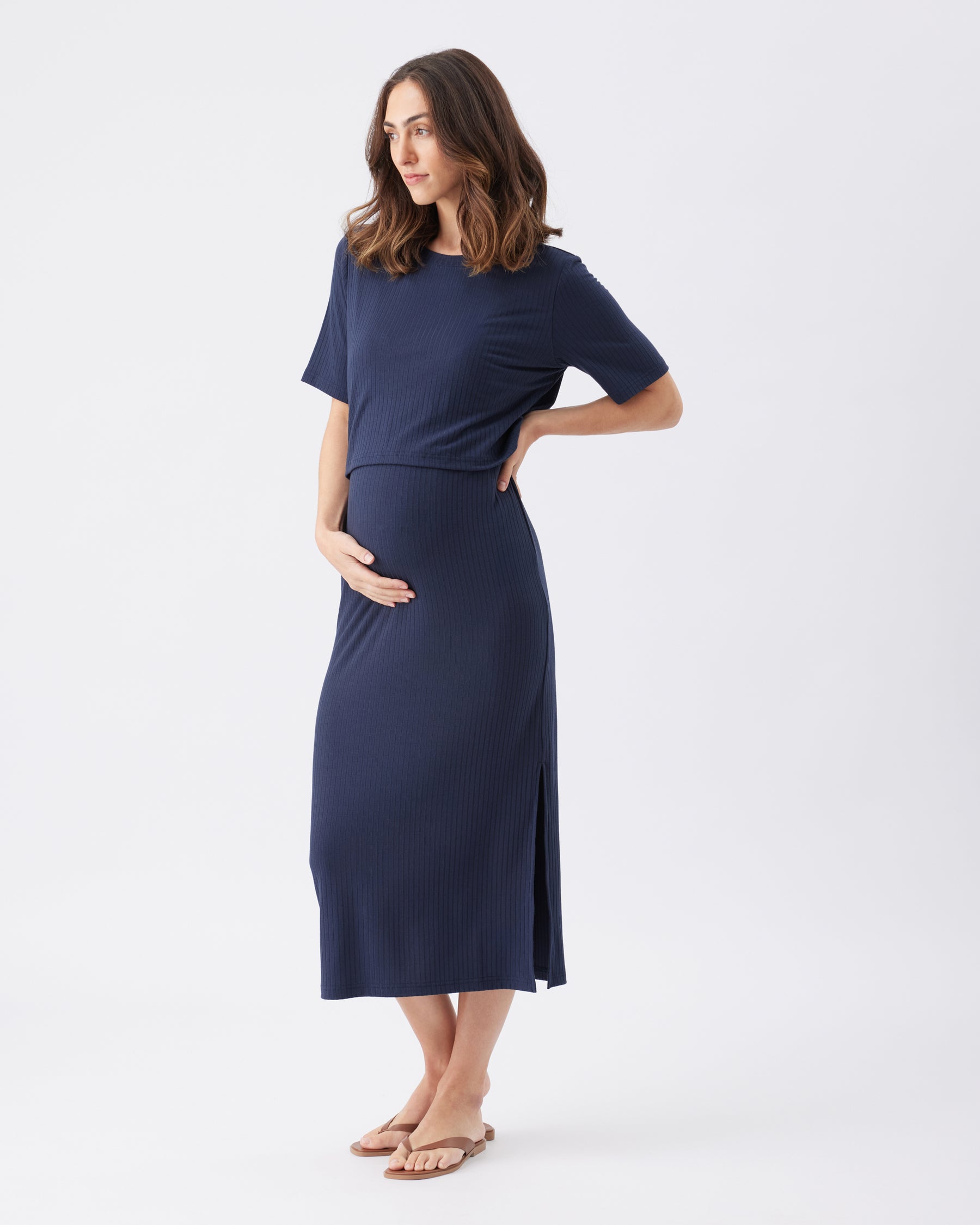 Side view of a pregnant woman wearing a navy blue dress on a white background
