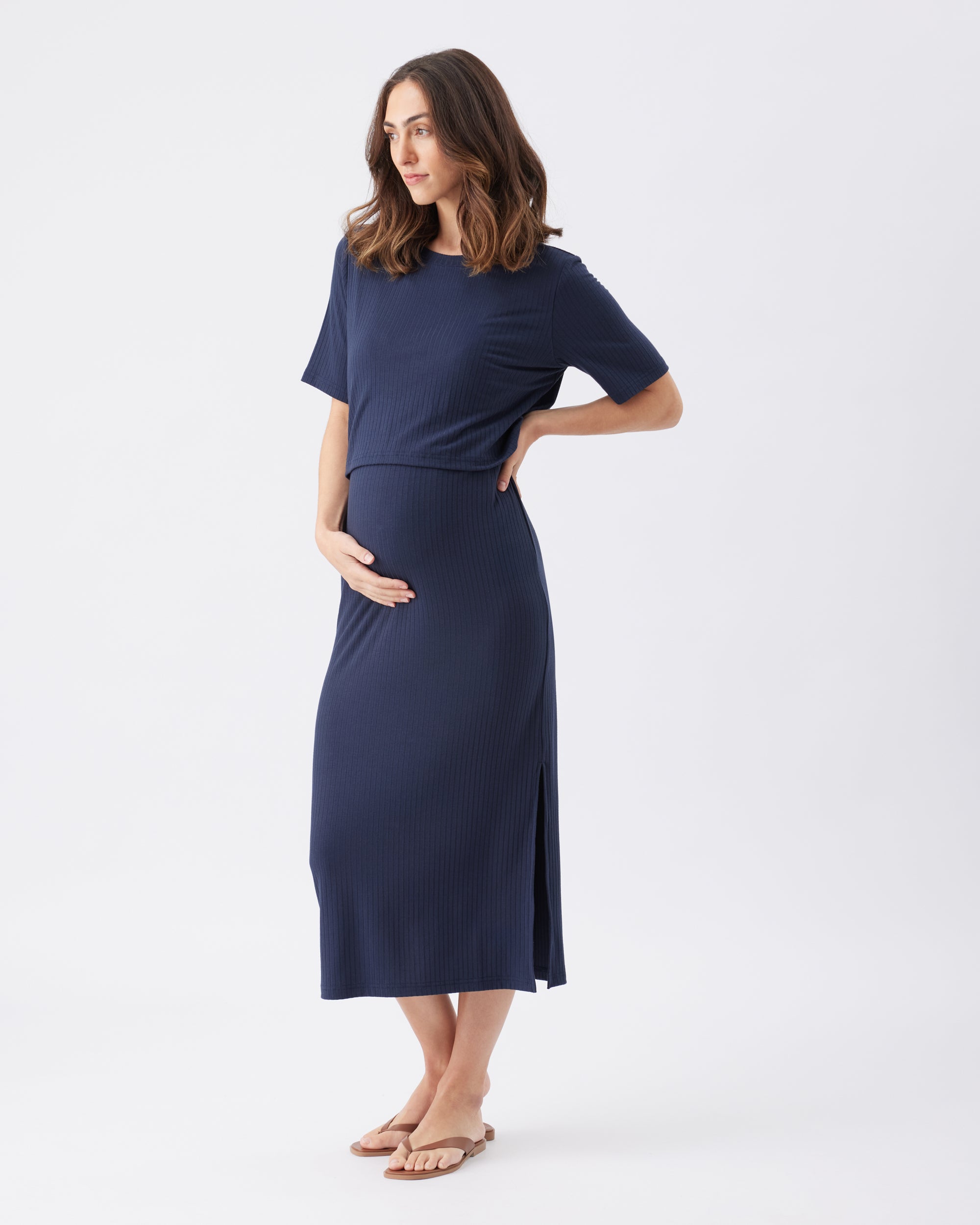 Side view of a pregnant woman wearing a navy blue dress on a white background