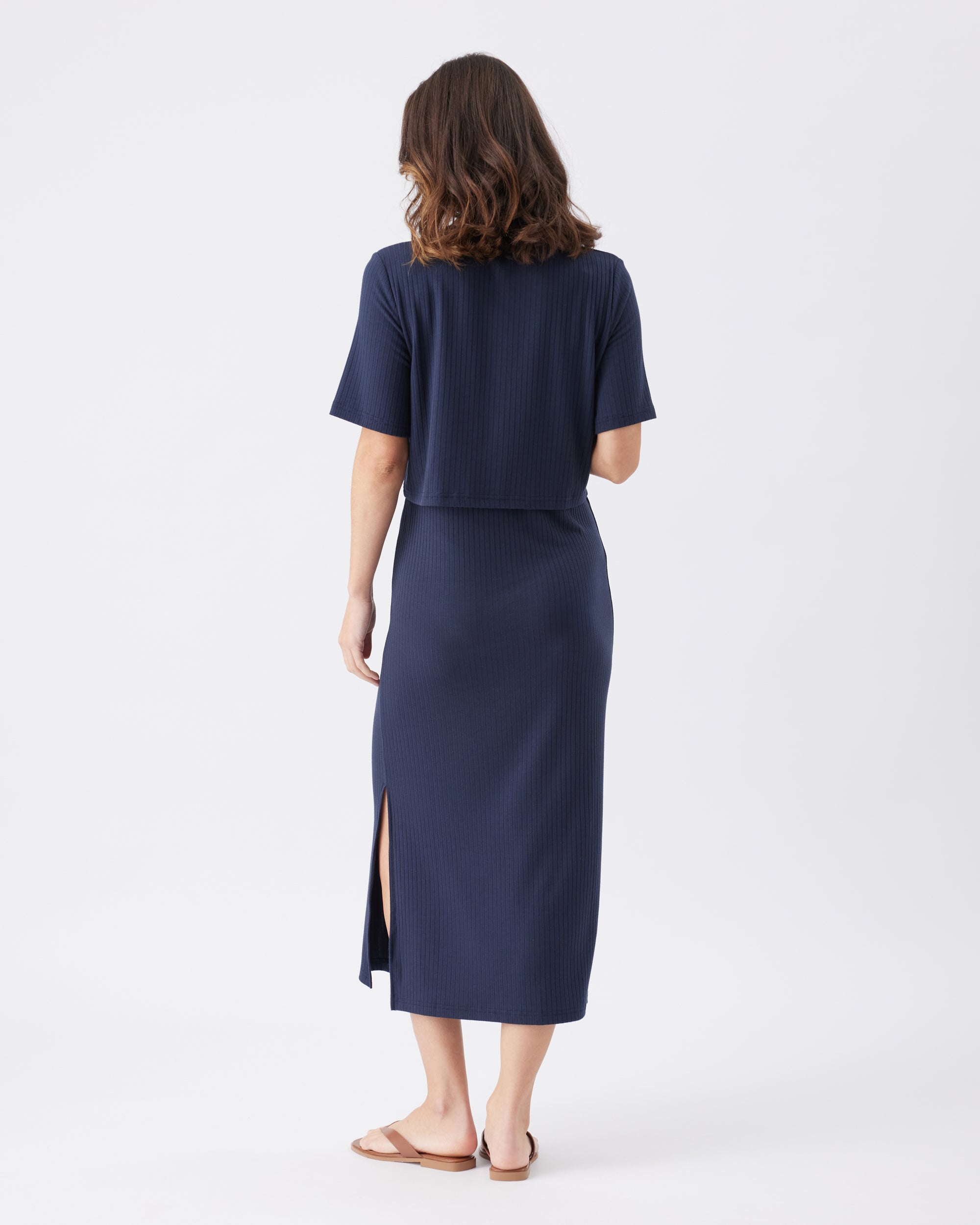 Back view of a woman wearing a navy blue midi dress on a white background