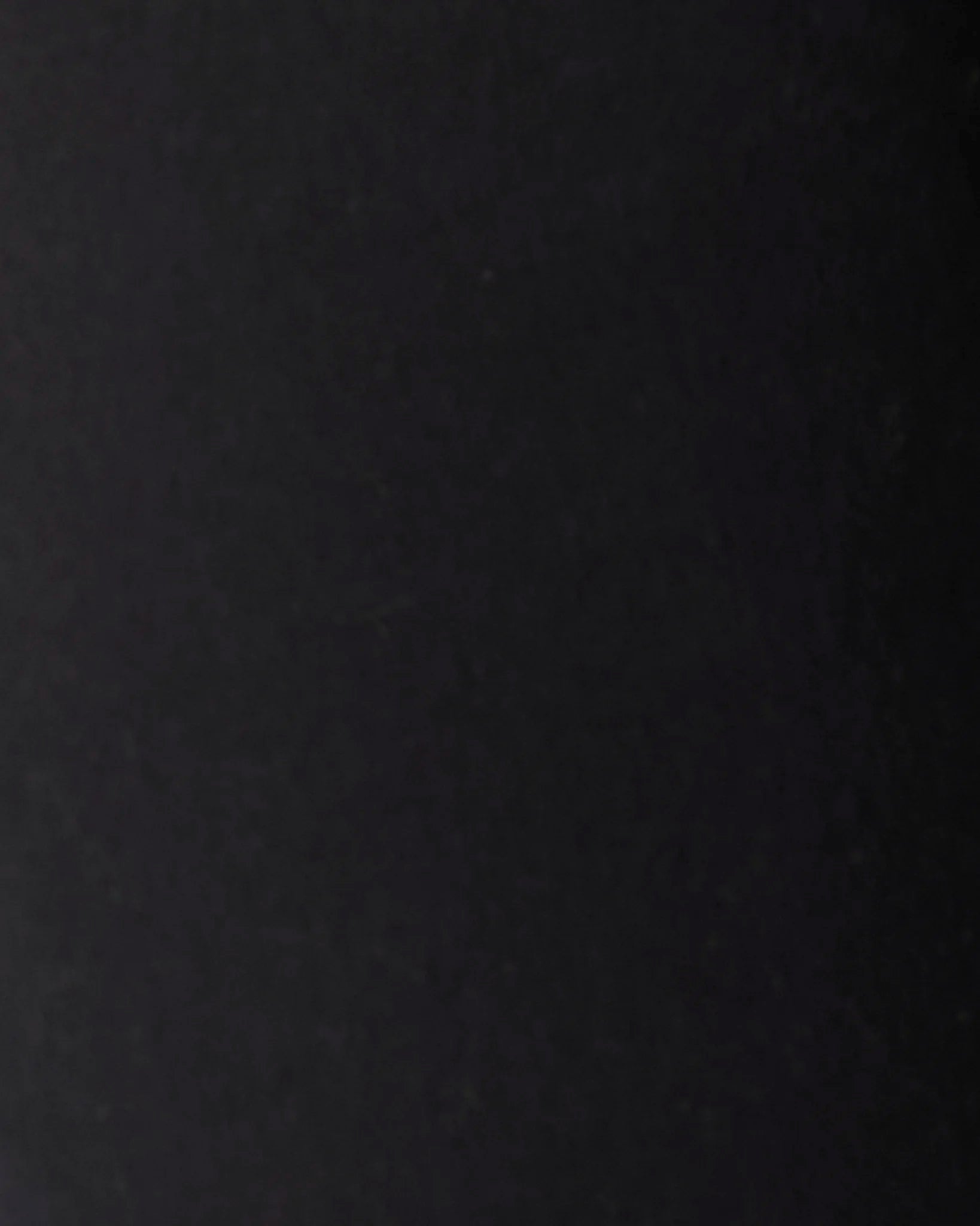 A close-up of a solid black textured surface, likely a fabric or leather material swatch.