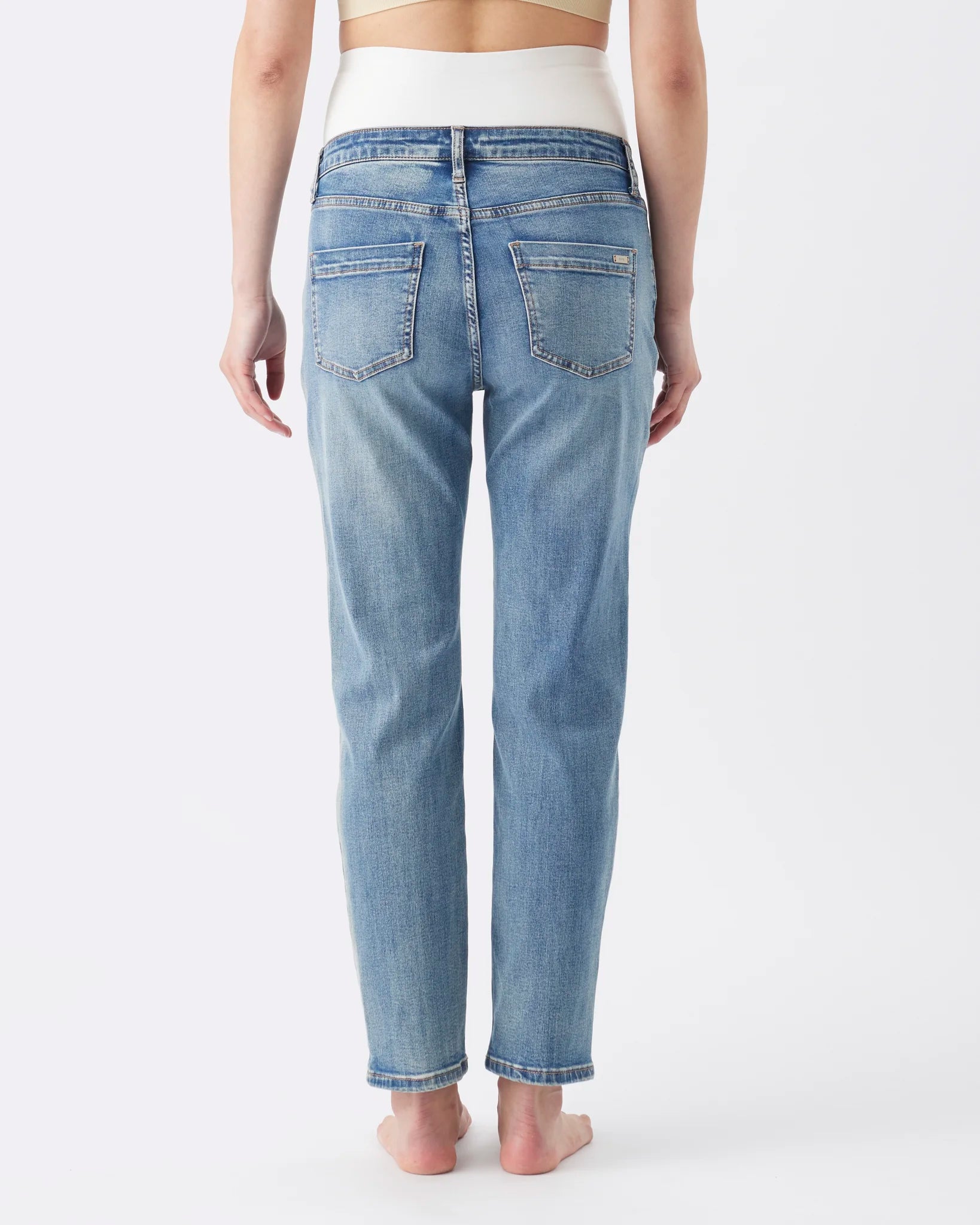 Rear view of a model wearing light-wash blue denim jeans with a straight-leg fit, shown against a plain white studio background.