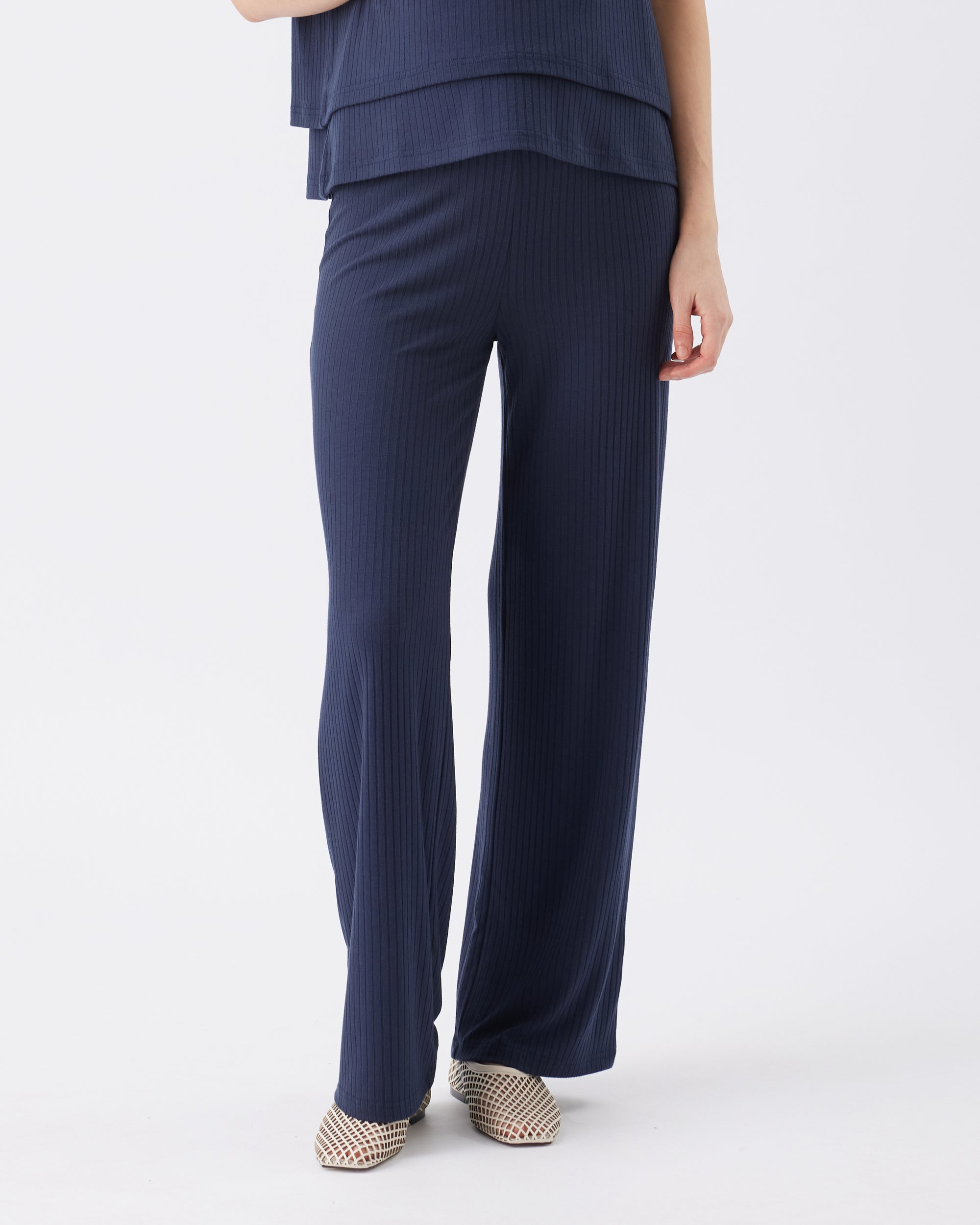 Navy ribbed pants worn by a pregnant person on a white background