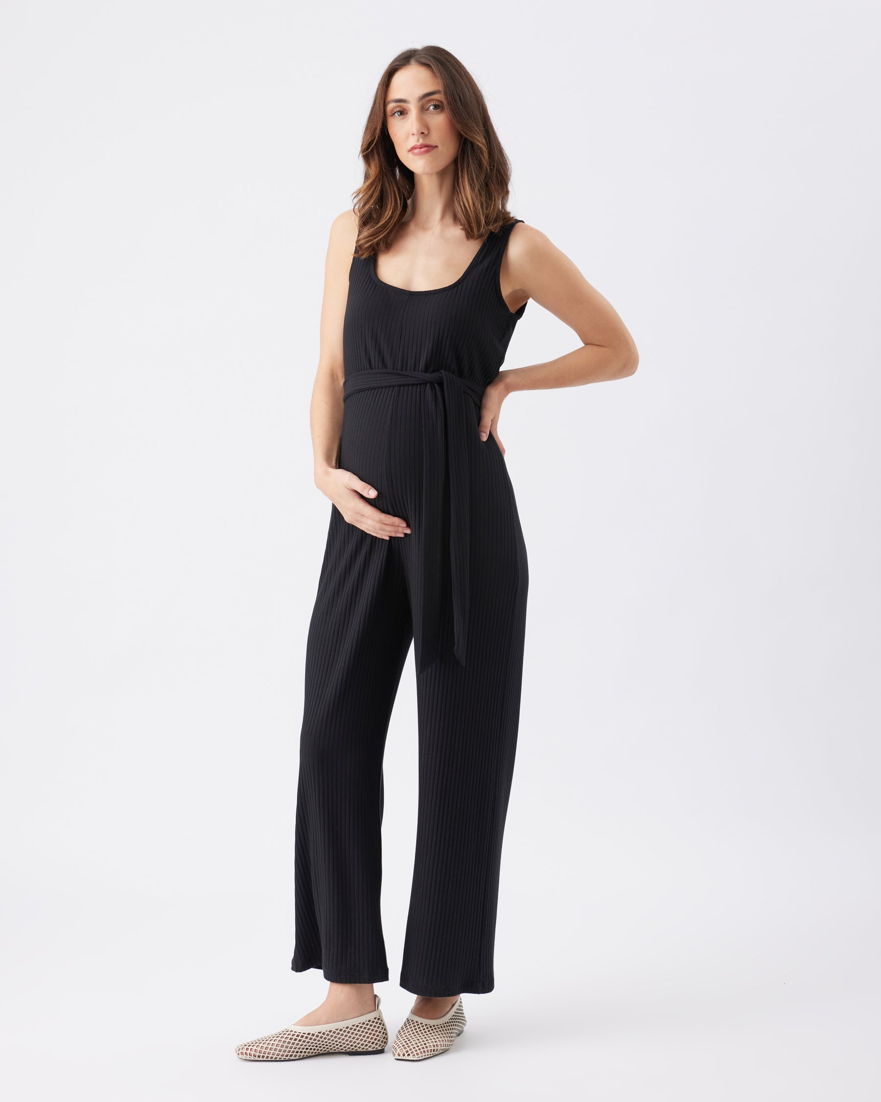 Woman wearing a black sleeveless jumpsuit on a white background