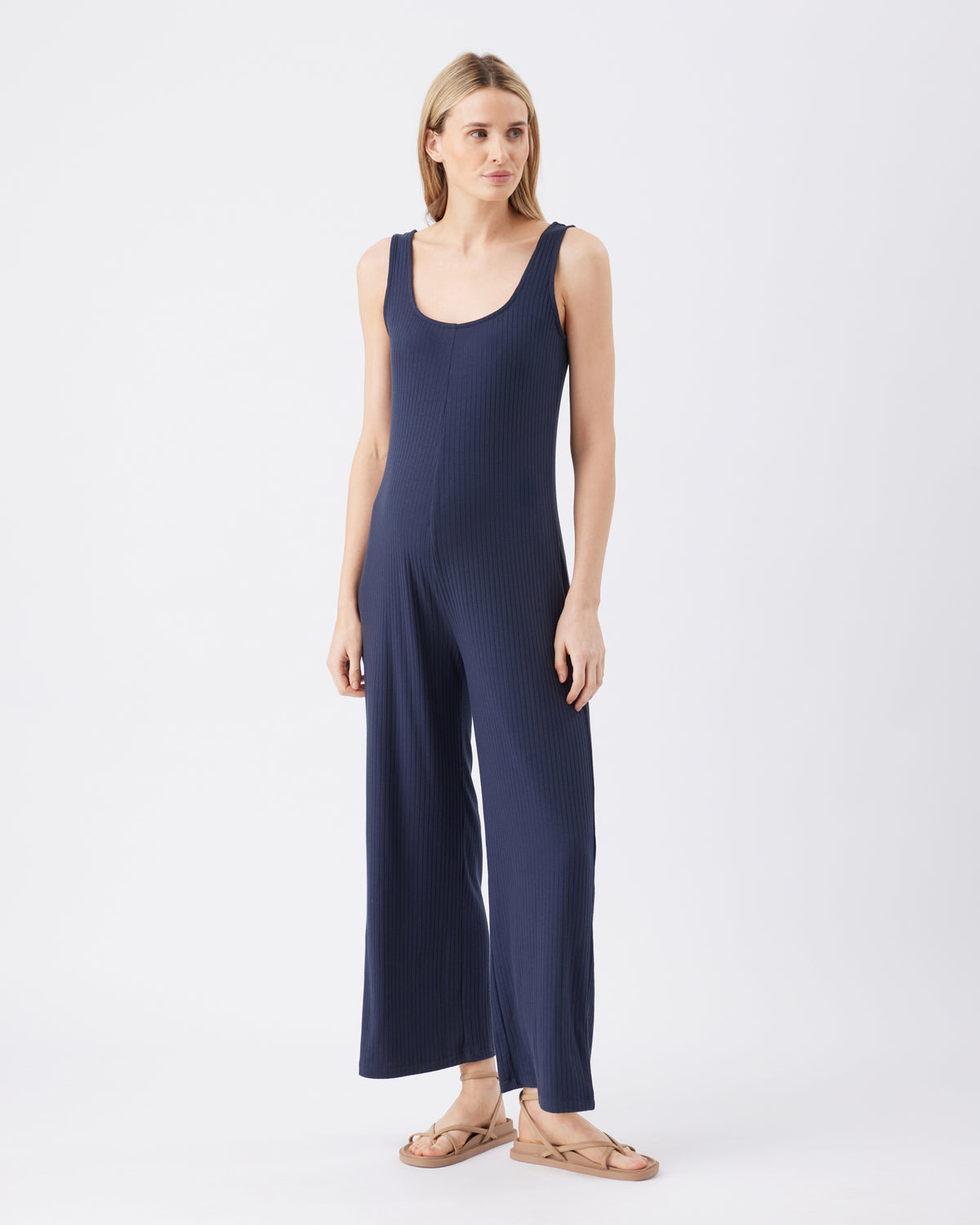 Full length image of a woman wearing a navy blue jumpsuit on a white background