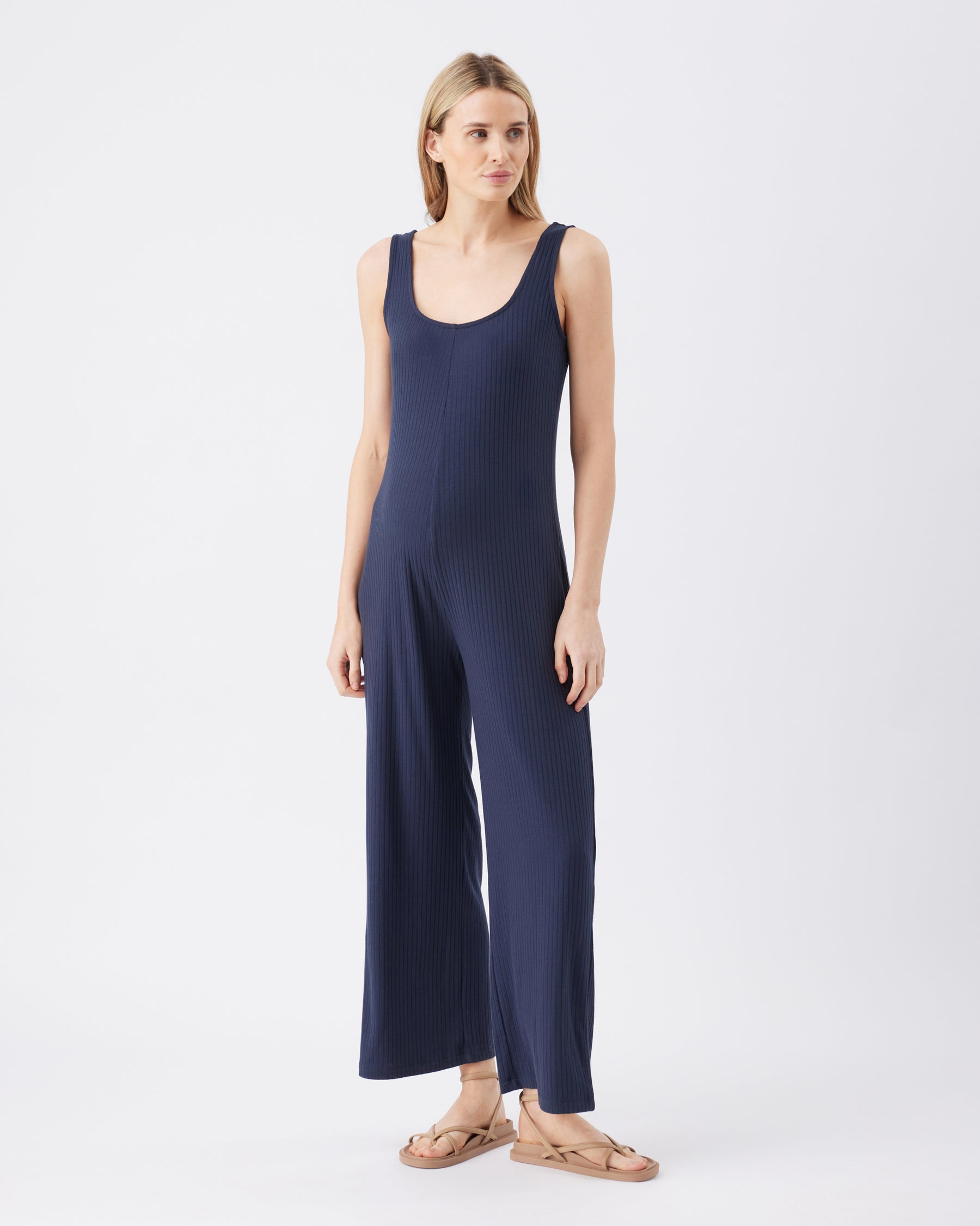 Full length image of a woman wearing a navy blue jumpsuit on a white background