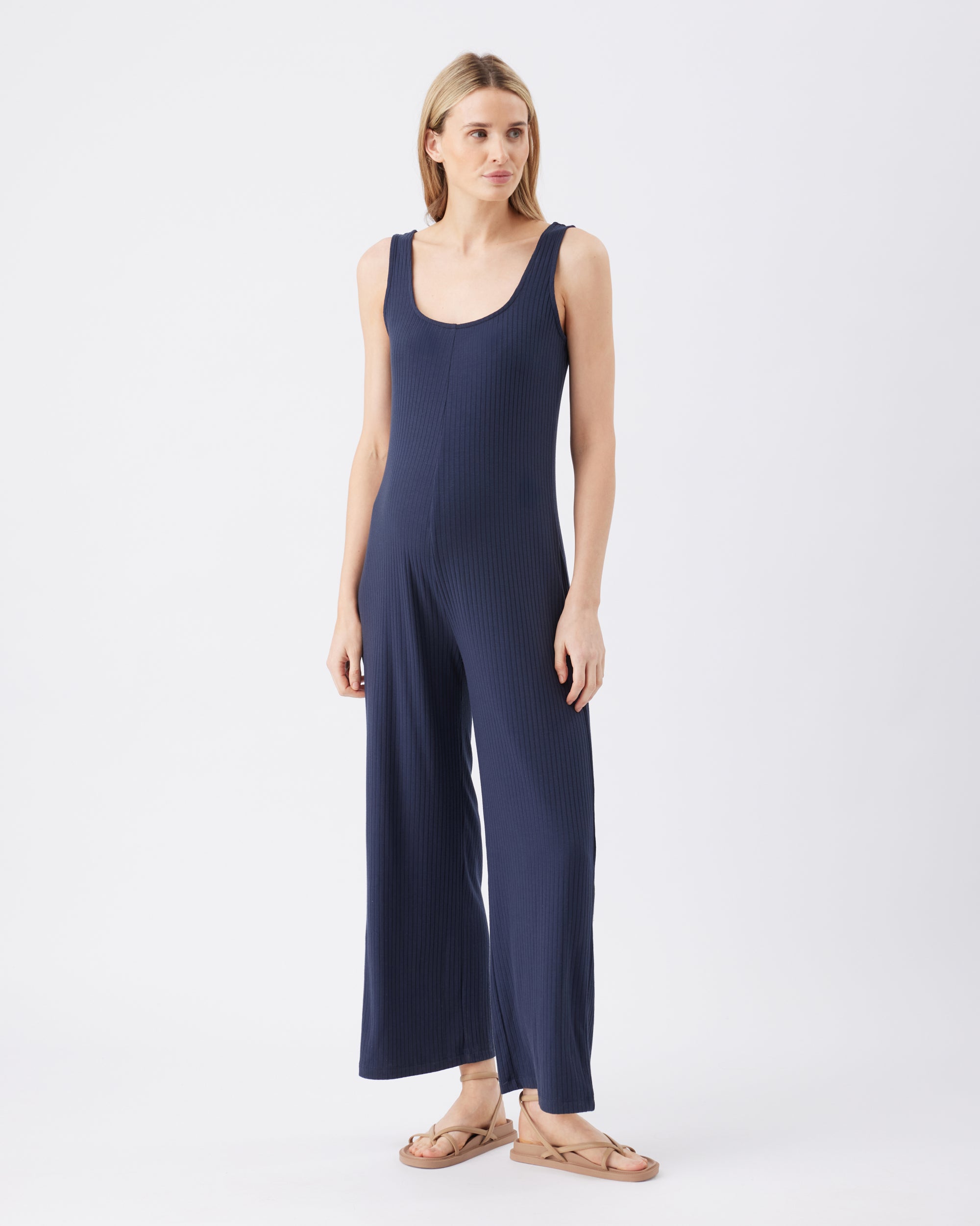 Full length image of a woman wearing a navy blue jumpsuit on a white background