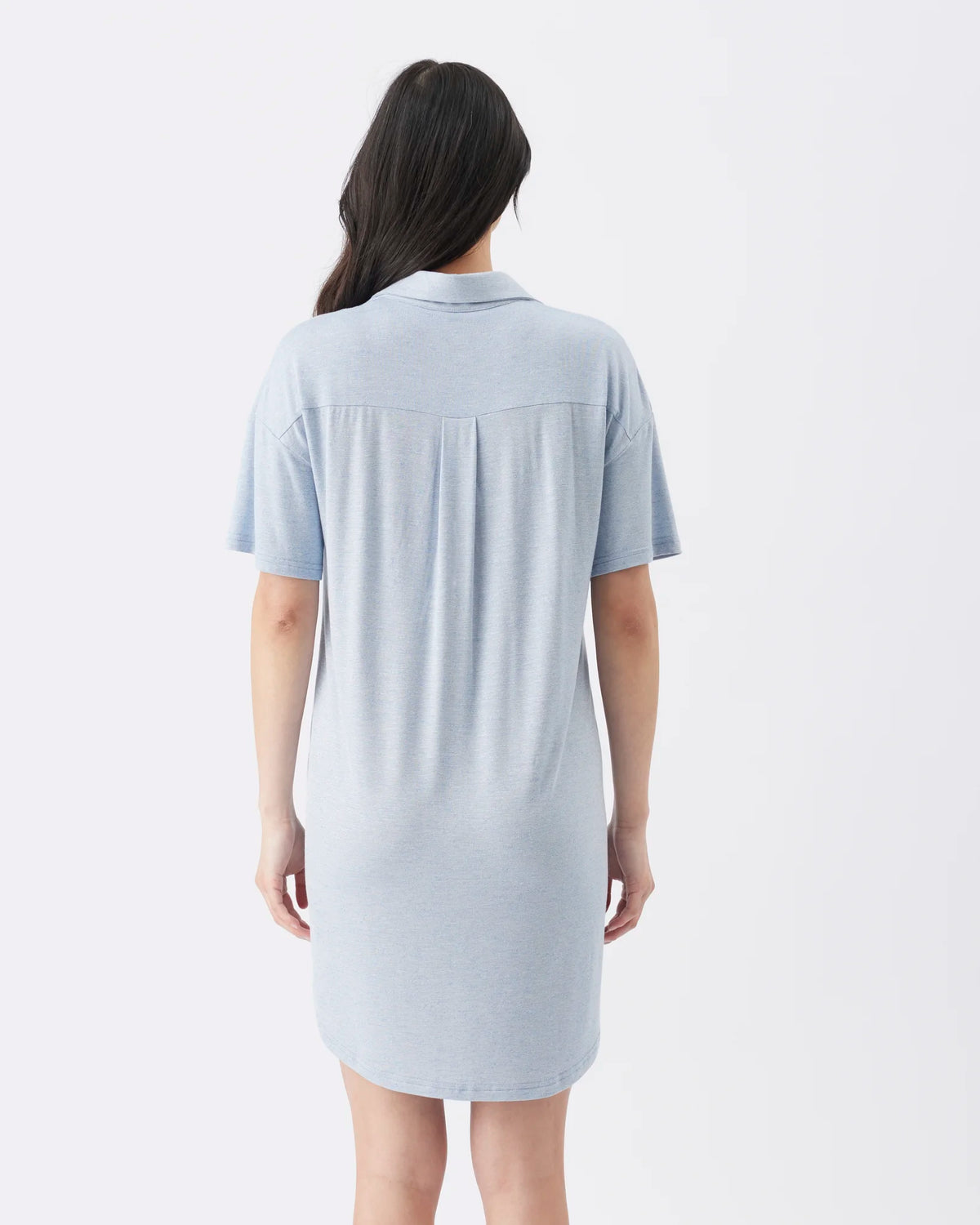 A woman viewed from the back wearing a light blue short-sleeve polo shirt dress against a plain white studio background.