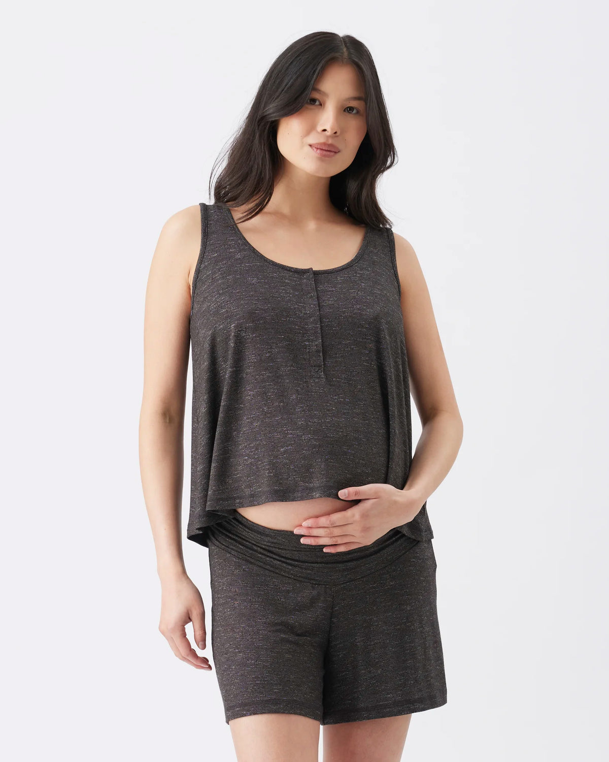 A pregnant woman modeling a dark gray heathered two-piece loungewear set consisting of a sleeveless cropped tank top with a split neckline and matching high-waisted shorts, against a plain white studio background.